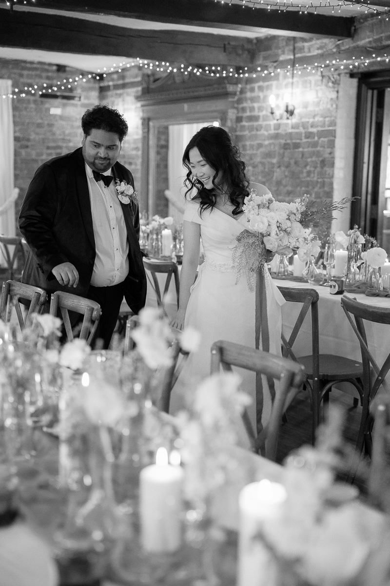 A couple admires their wedding reception decor with candlelit tables and twinkling lights overhead.