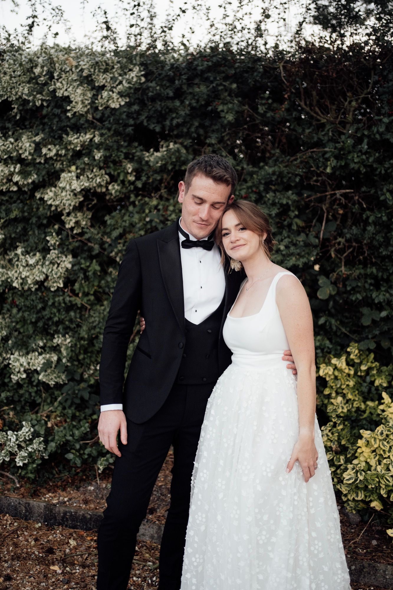 A romantic outdoor wedding photoshoot with a couple in formal attire embracing against a backdrop of lush greenery  at Larkspur Lodge