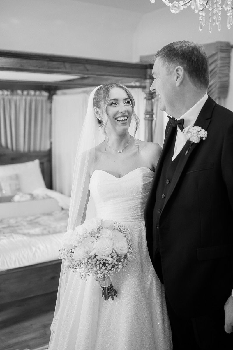 A joyful black and white wedding moment captured indoors with a beautiful bouquet of white flowers.