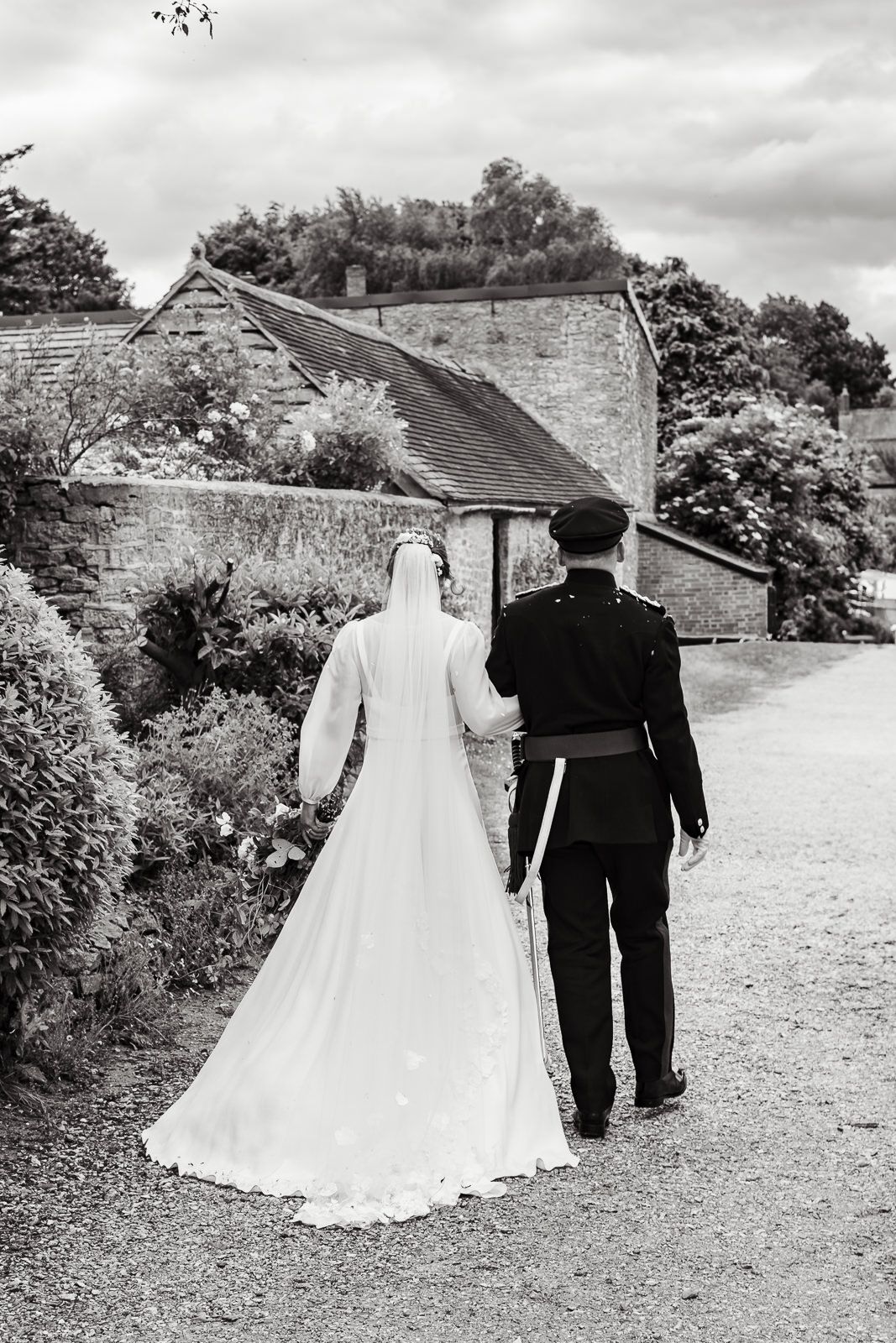 A romantic black and white photo sequence showing a couple walking away along a countryside path at their wedding.