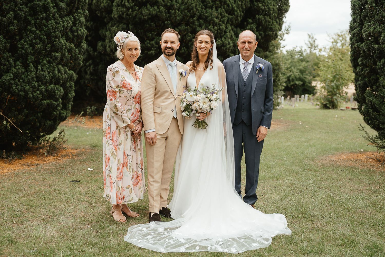 Wedding party poses together outdoors on grassy lawn during summer celebration.