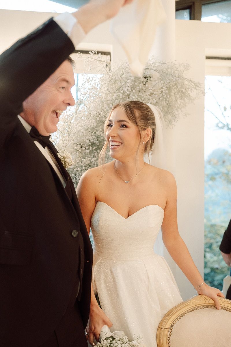 A joyful wedding moment captured between a bride in a strapless white gown and someone in a black tuxedo.
