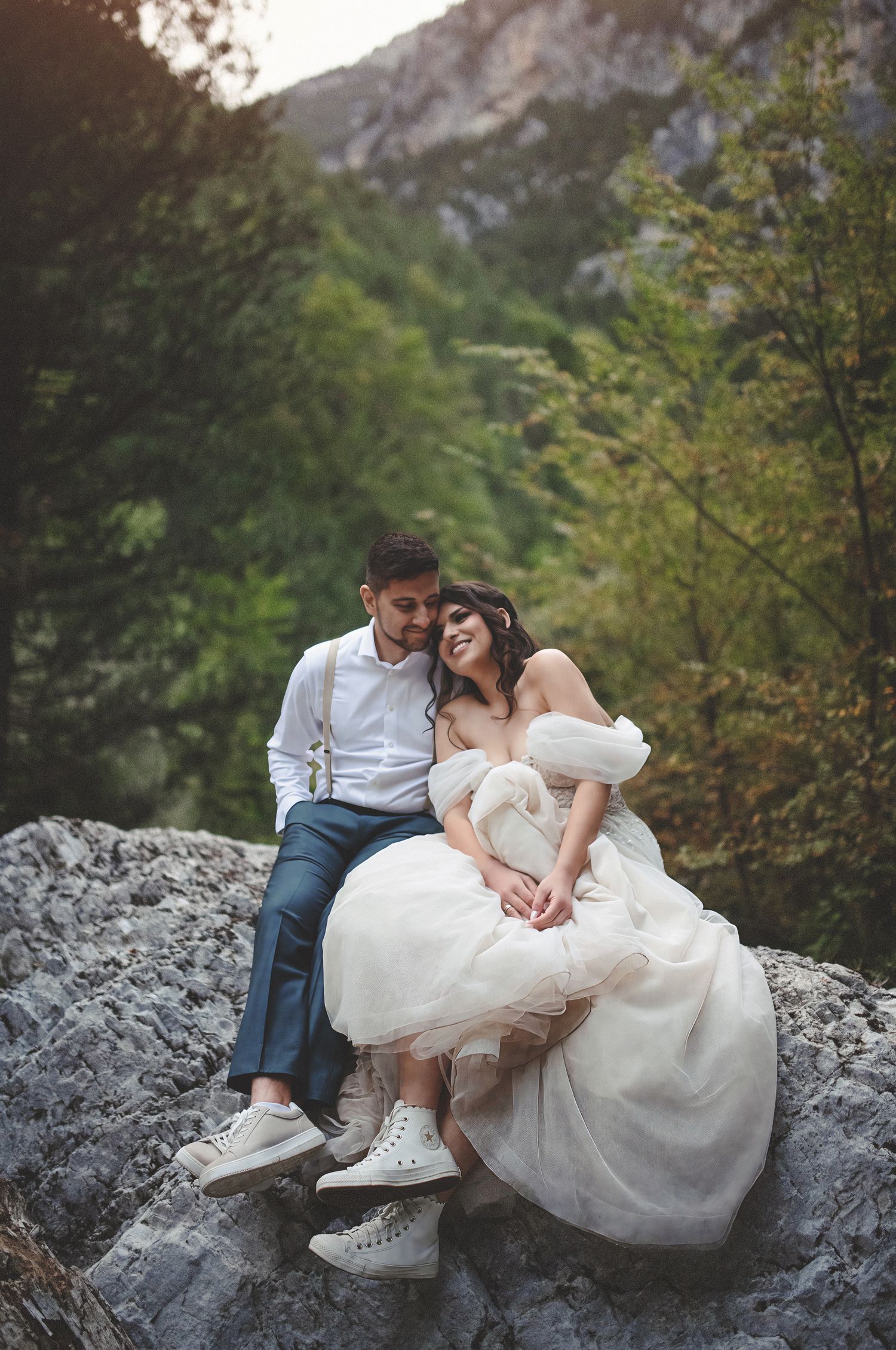 Adventure elopement wedding photography featuring a bride and groom in sneakers sitting on a mountain rock.