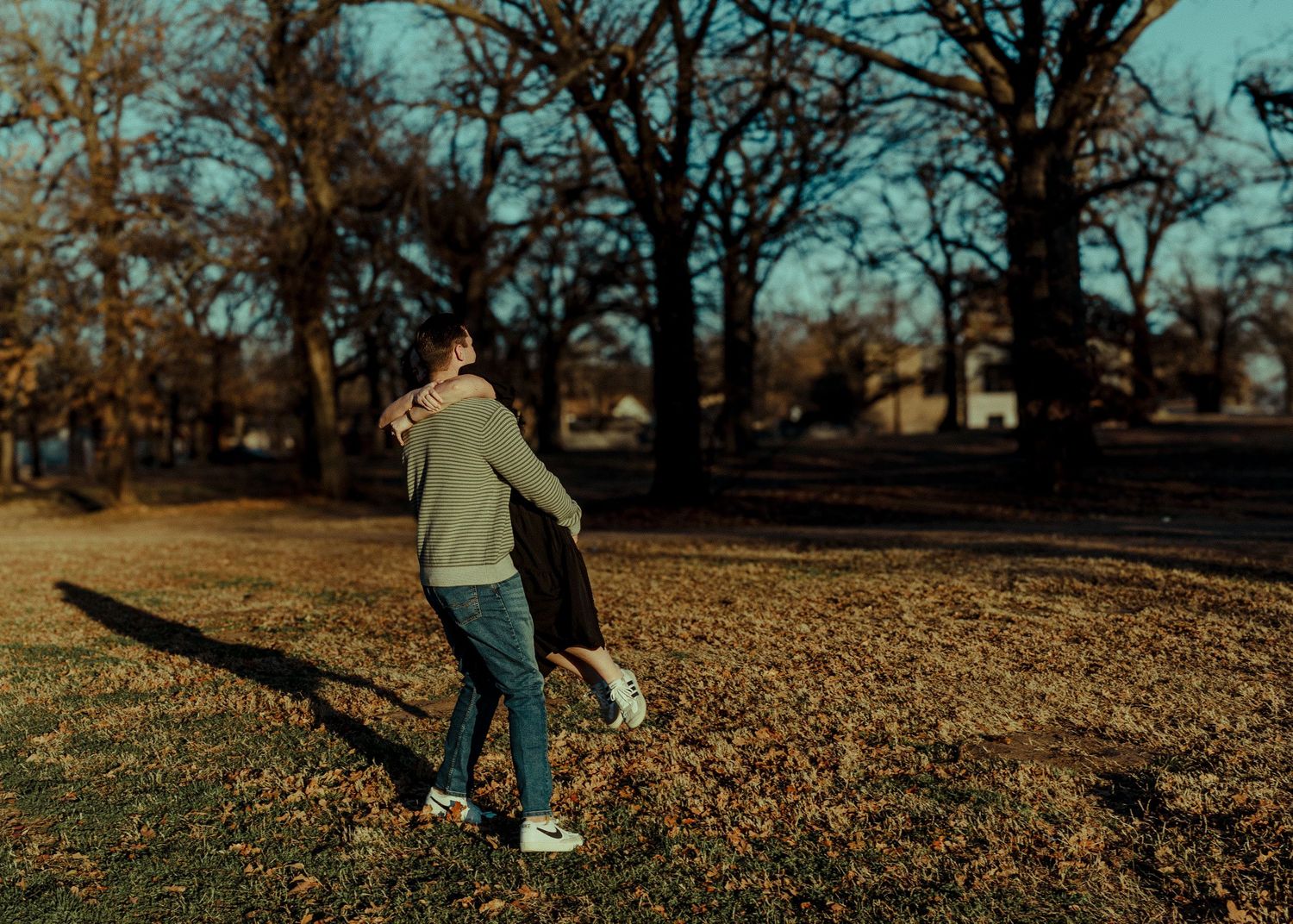 A couple embraces while dancing together on a sunny autumn day in a park. Oklahoma City couple photoshoot.