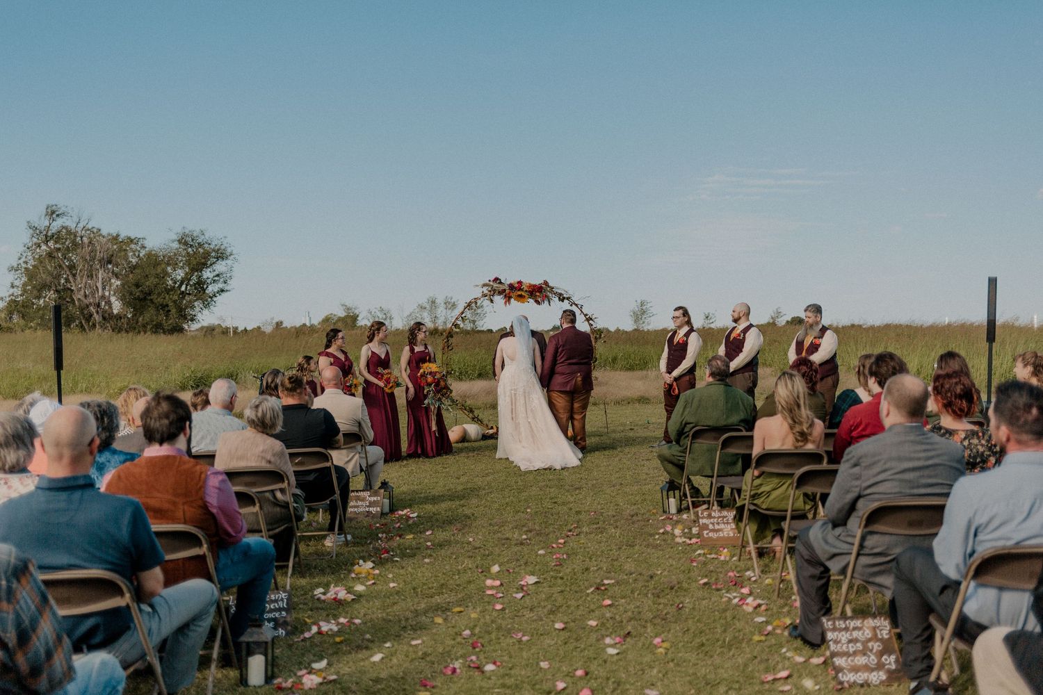 Outdoor wedding ceremony with guests seated in open field under blue sky. Esperanza Ranch wedding ceremony