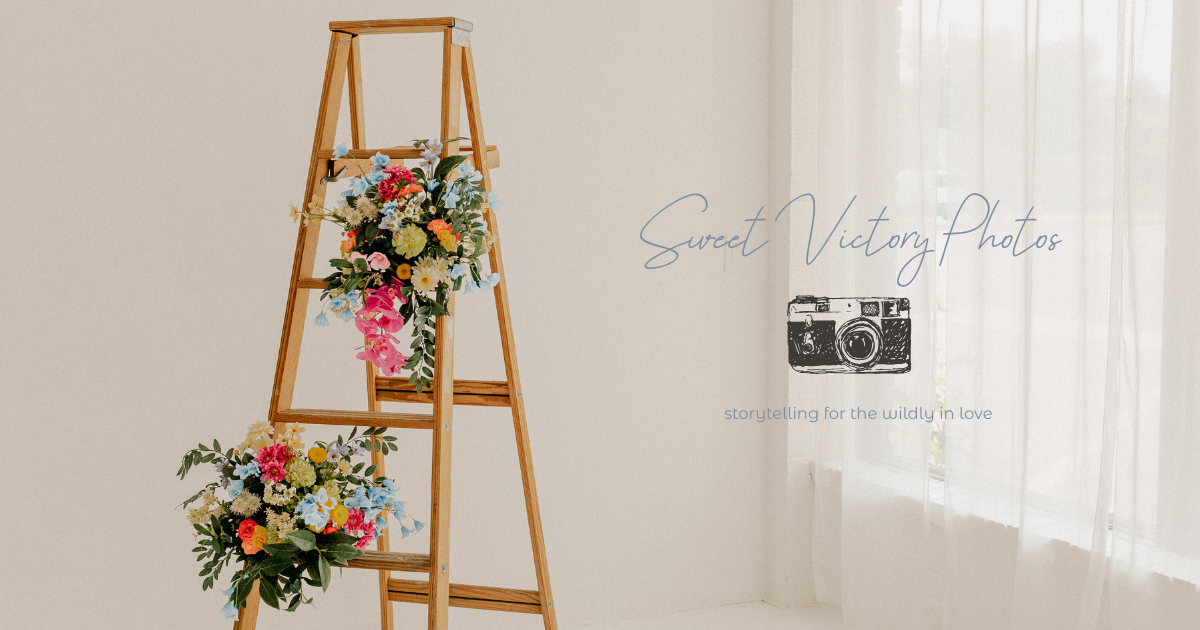 Sweet Victory Photos studio banner with wooden ladder decorated with colorful floral arrangements. Oklahoma City based wedding photographer.