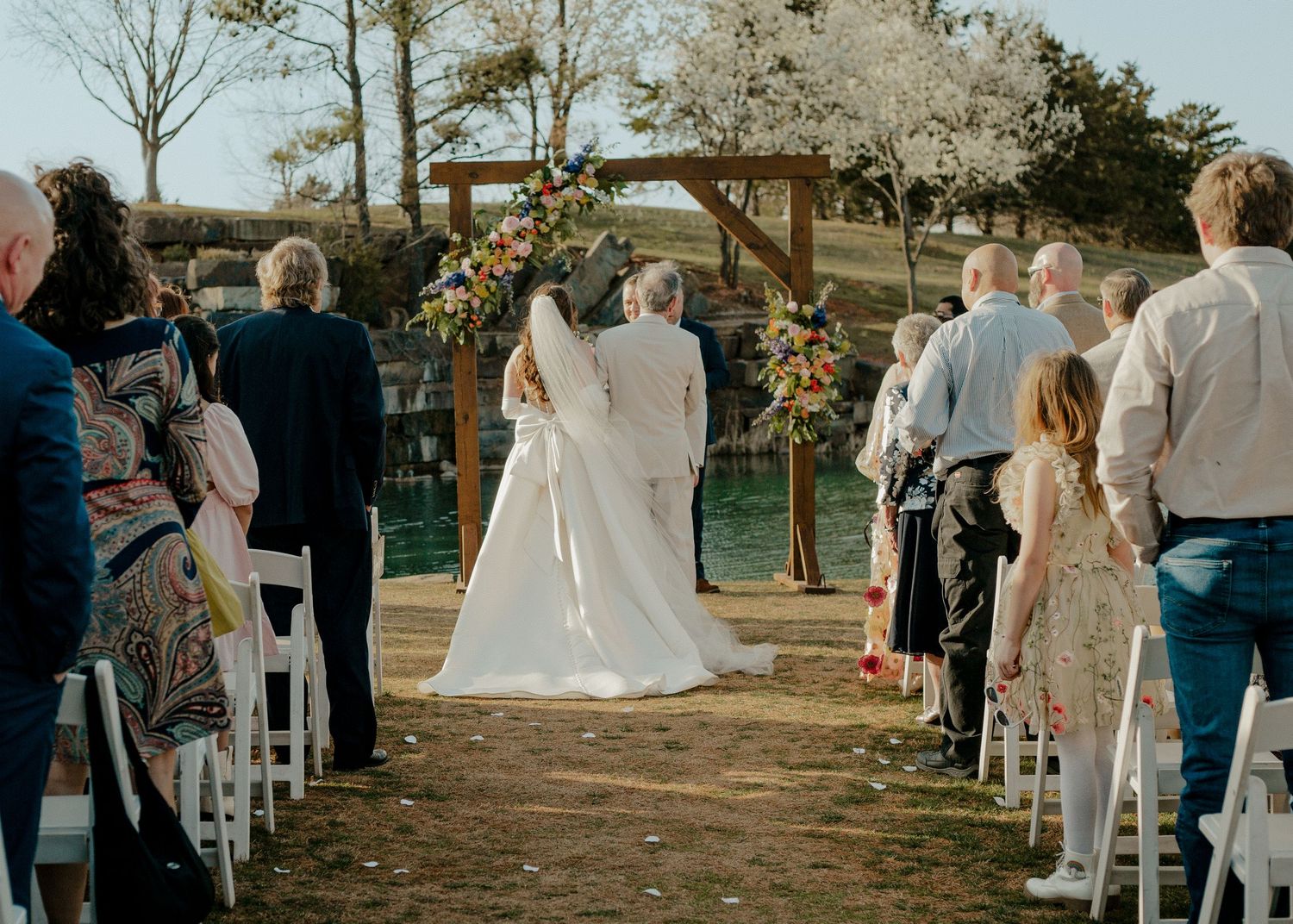 Bride and groom exchange vows at an outdoor wedding ceremony beneath a floral wooden arch. Esperanza Ranch in Oklahoma