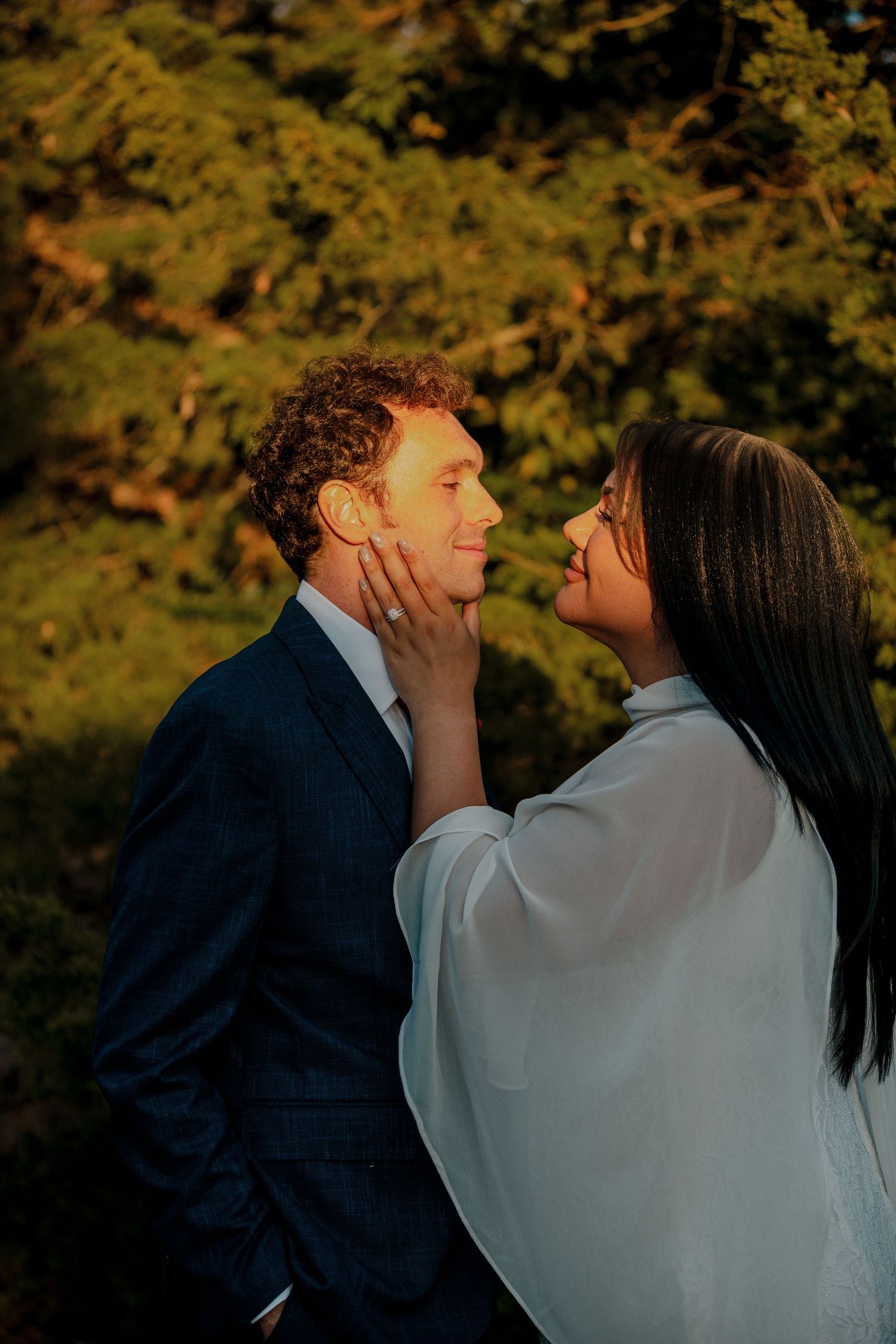 Couple sharing a tender moment at golden hour, woman gently cupping mans face outdoors. Oklahoma City intimate fall wedding.