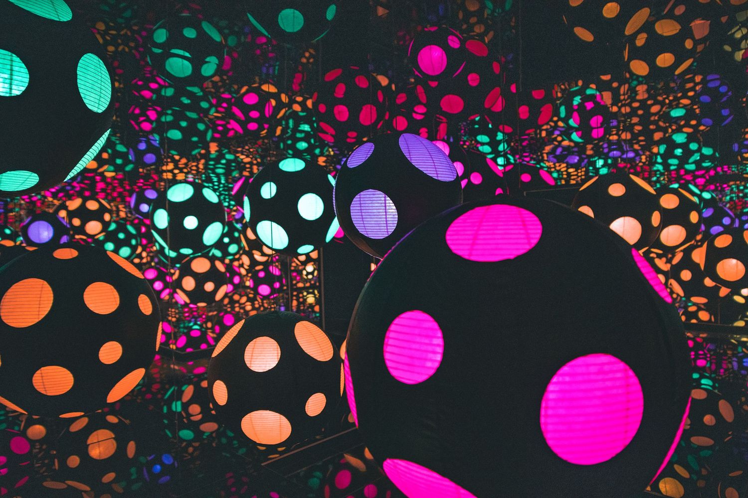 Vibrant colorful polka dot illuminated spheres in immersive neon art installation display.