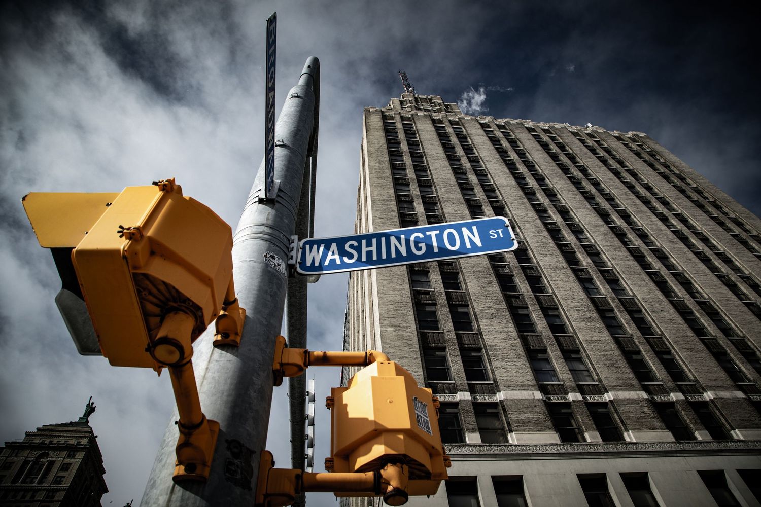 Low angle view of Washington Street sign with traffic lights against dramatic cloudy urban skyline.