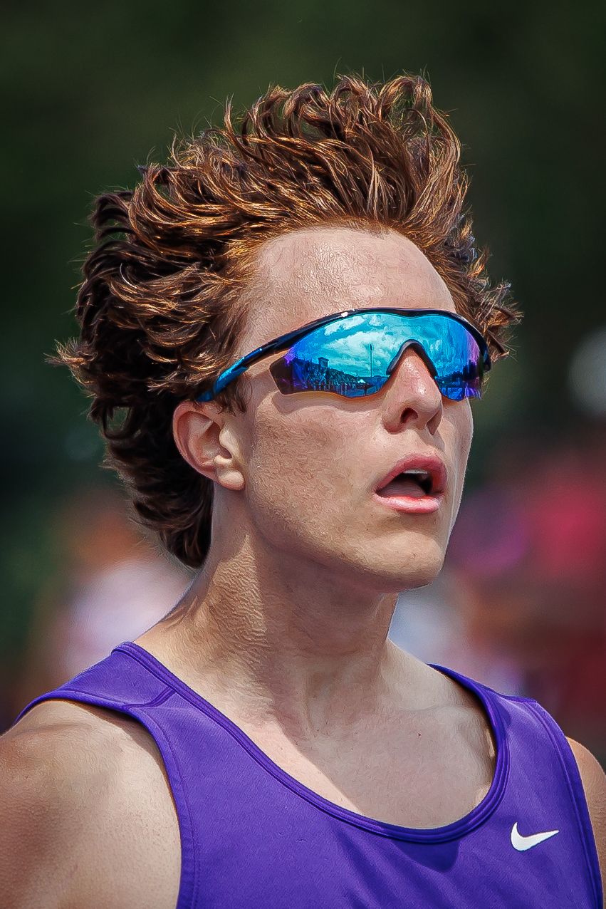 Male runner in purple Nike tank with wild hair and blue mirrored sunglasses.