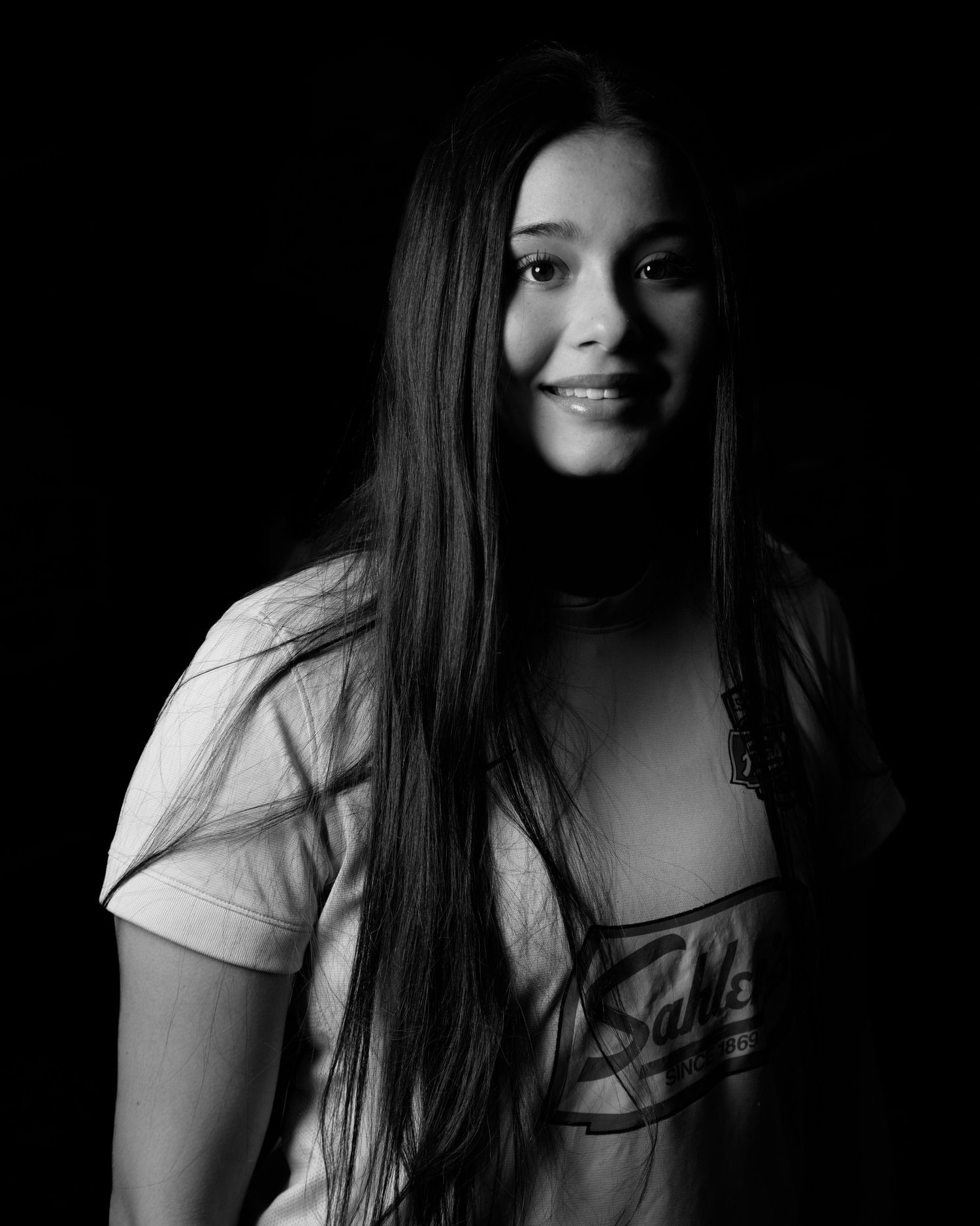Black and white portrait of a smiling young female soccer player in a Sahlens jersey.