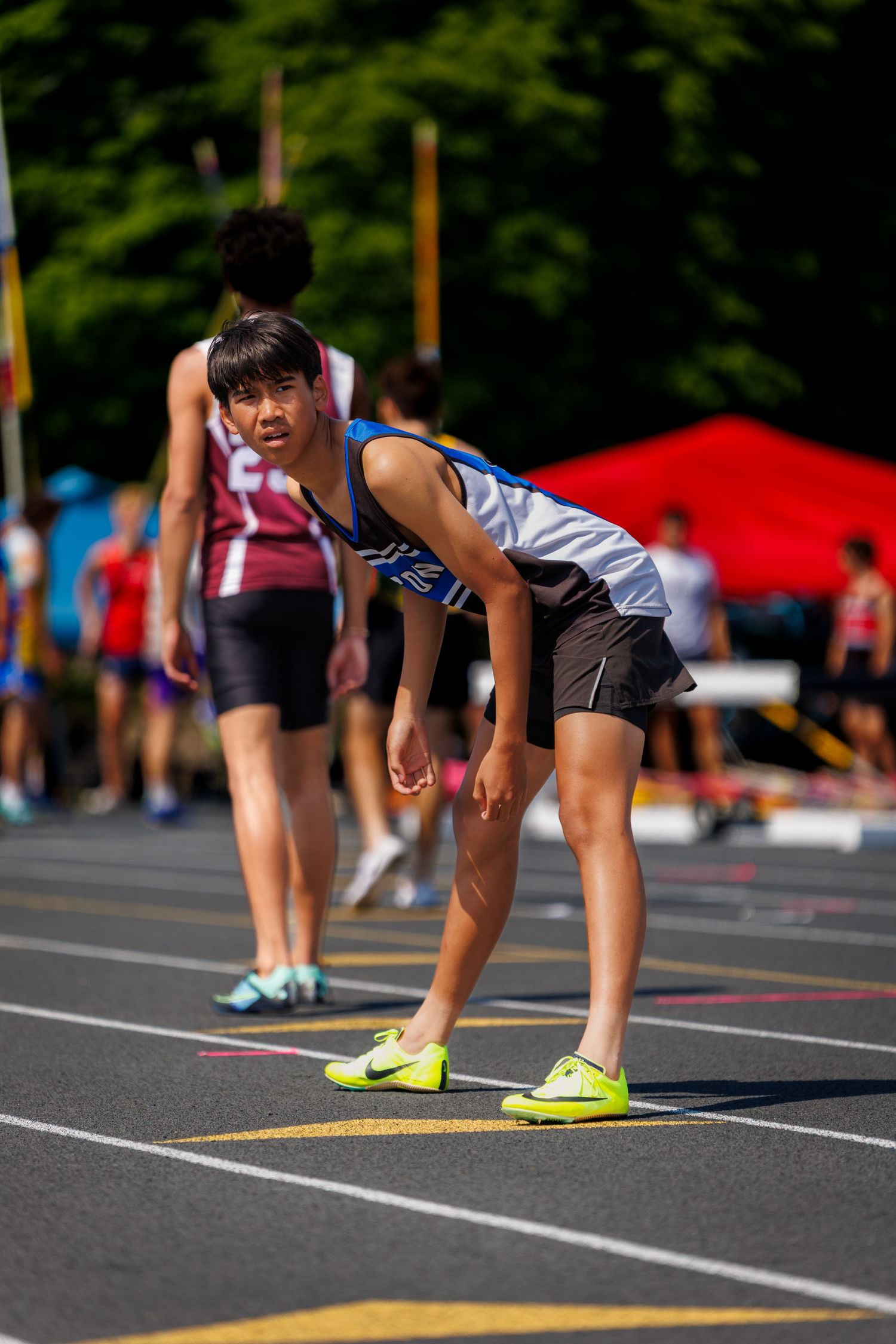 Young female track athlete in starting position on outdoor running track.