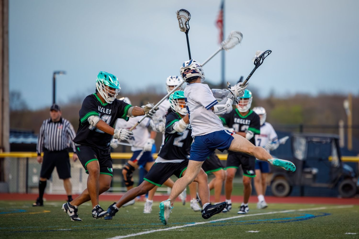 Lacrosse players battle for possession during an intense game, with players in green and white uniforms.