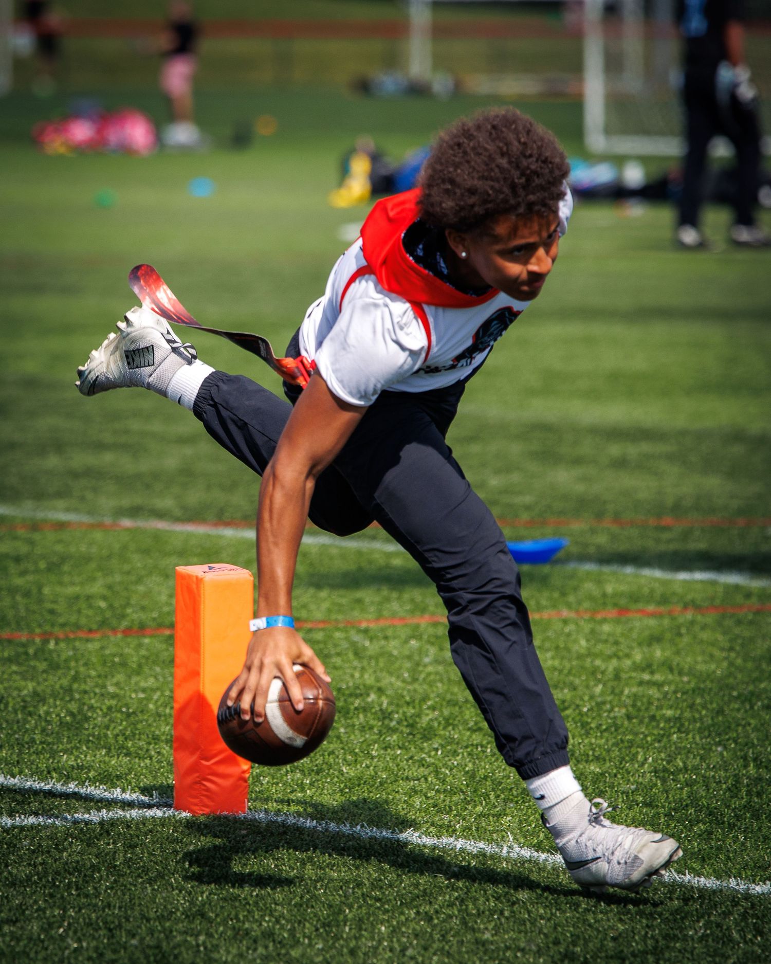 Young football player dives toward the end zone pylon with the ball outstretched during a flag football game.