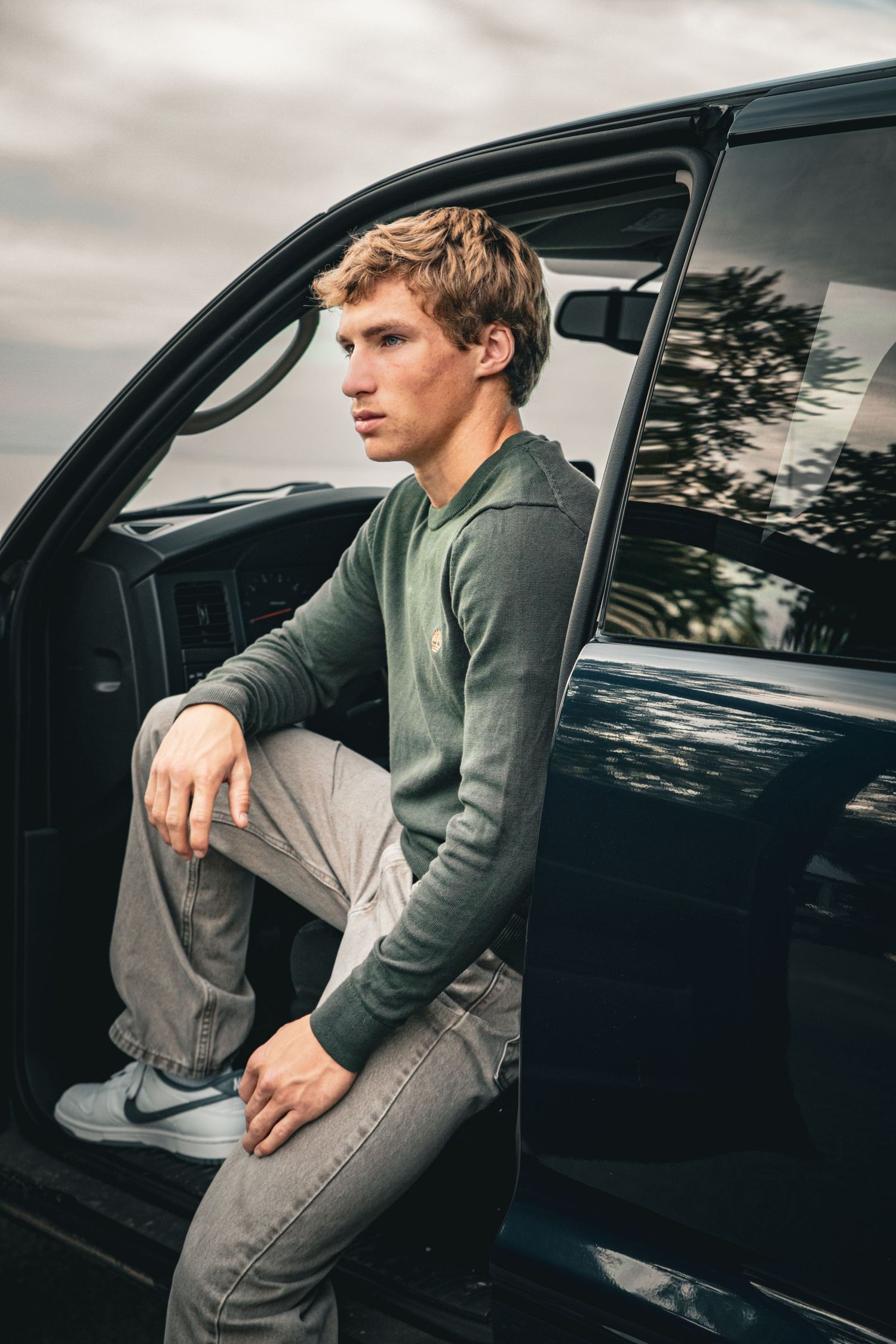 Senior portrait seated beside a blue pickup truck