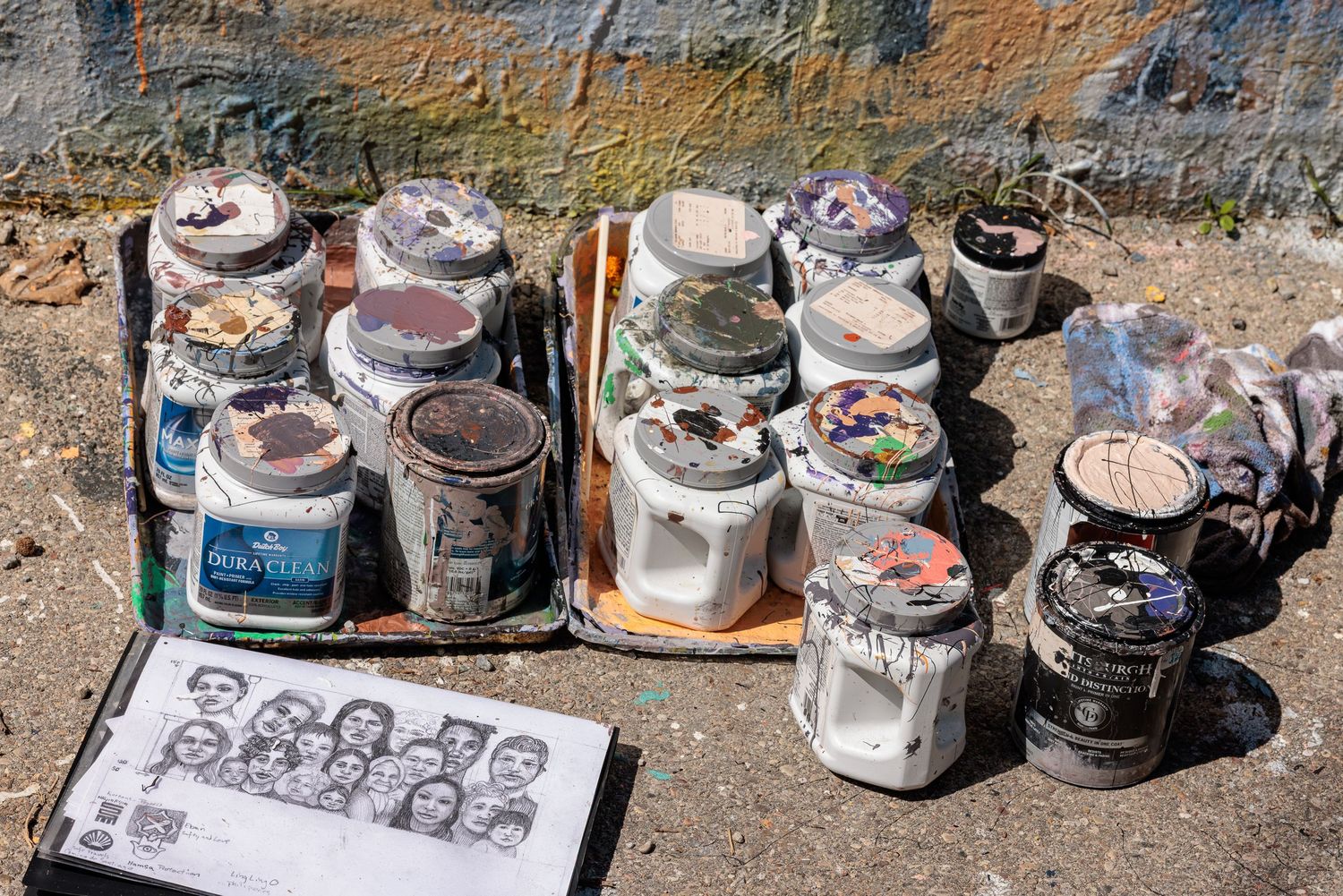 Still life of paint buckets and a small reference sketch of faces on the ground