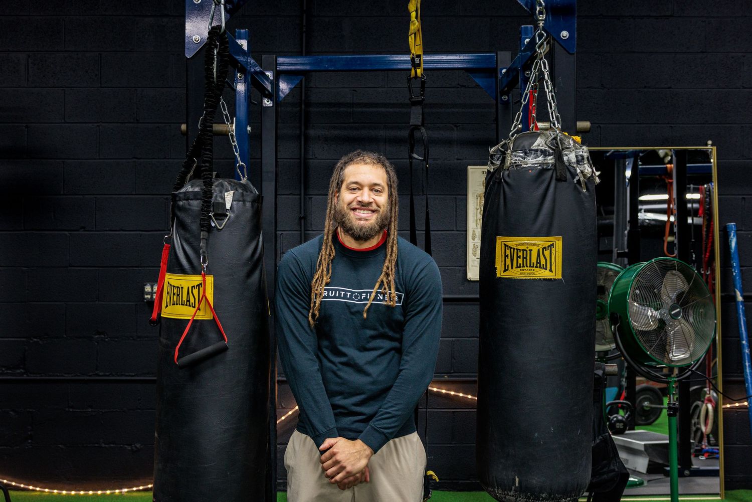 Man standing in a boxing gym in front of punching bags and training equipment