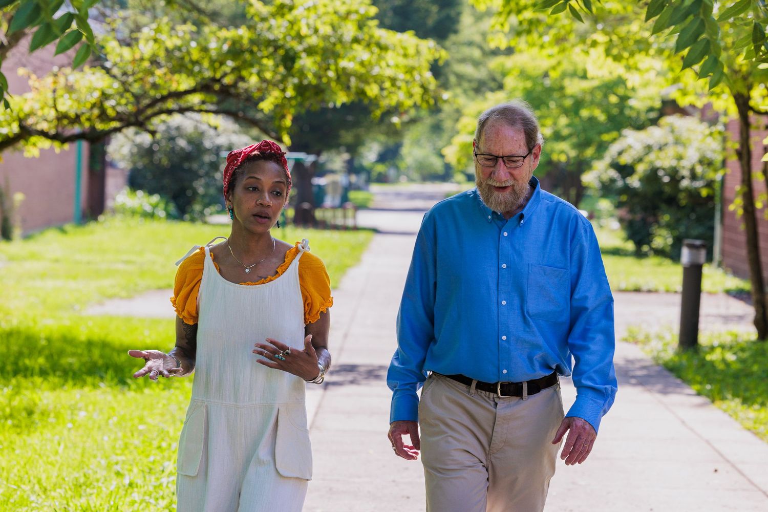 Hyacinth and Roi walking together along a tree-lined path on campus
