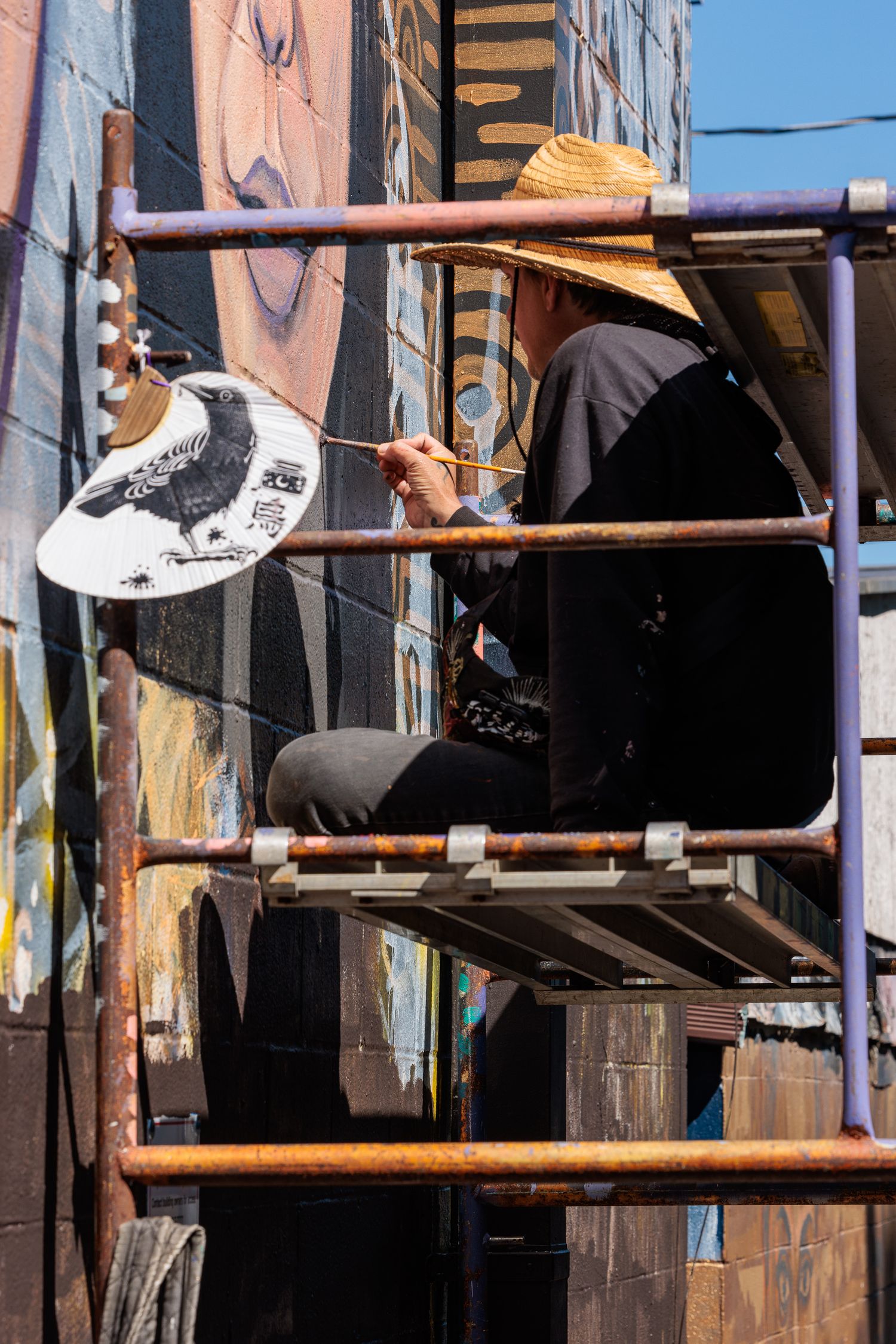 Muralist Pierre Nagley holding a paint palette while working from scaffolding