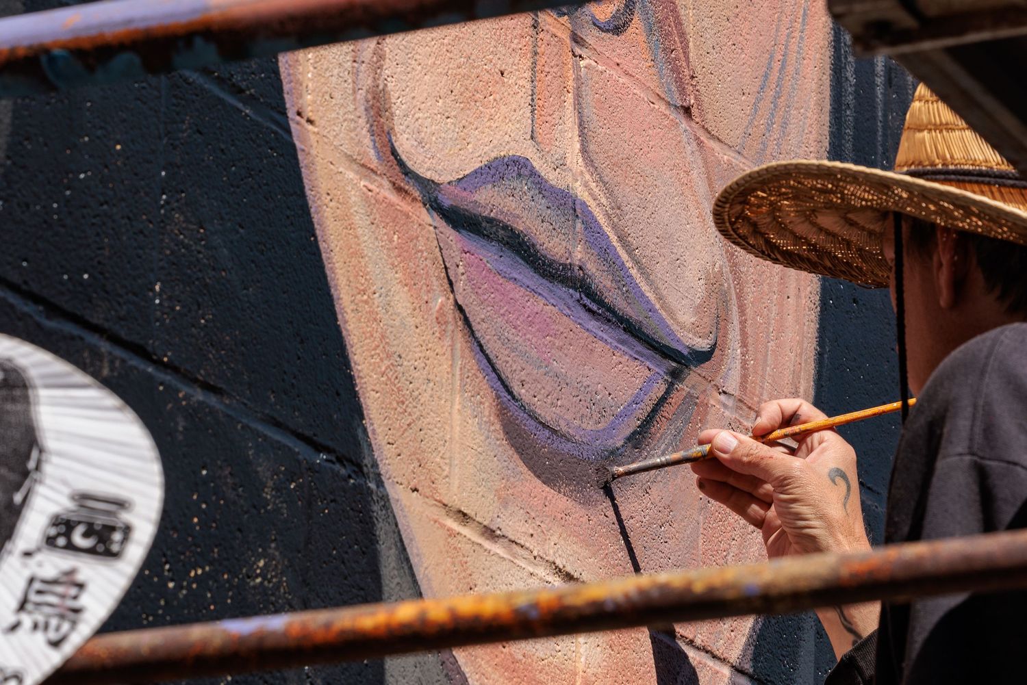 Close-up of an Muralist Pierre Nagley's hand painting lip detail on a mural portrait