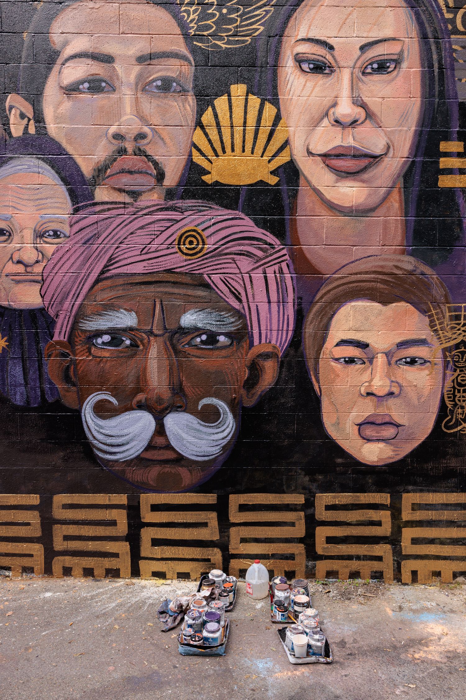 Close-up of painted mural faces with paint-splattered shoes visible at the base of the wall