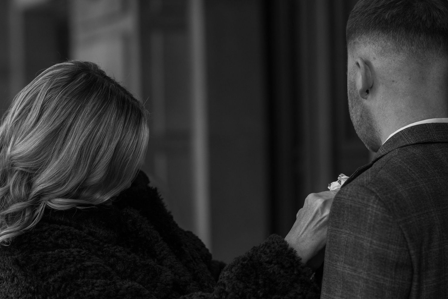Mother putting boutonnière on son before wedding