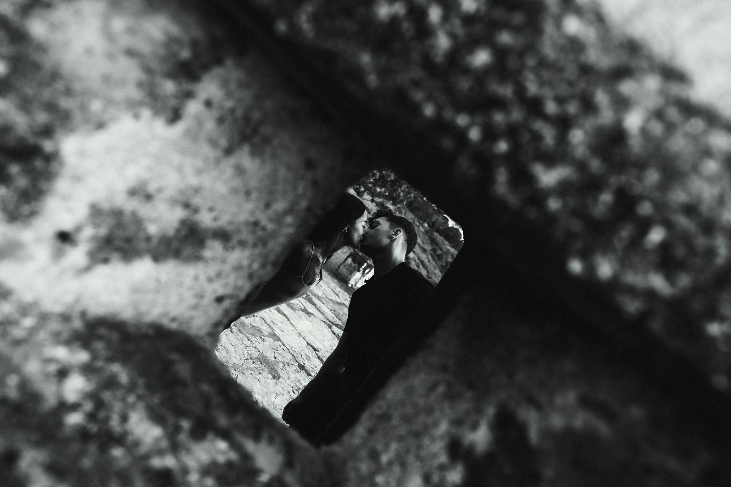 Black and white macro photo of a small rock fragment wedged between two larger stones.