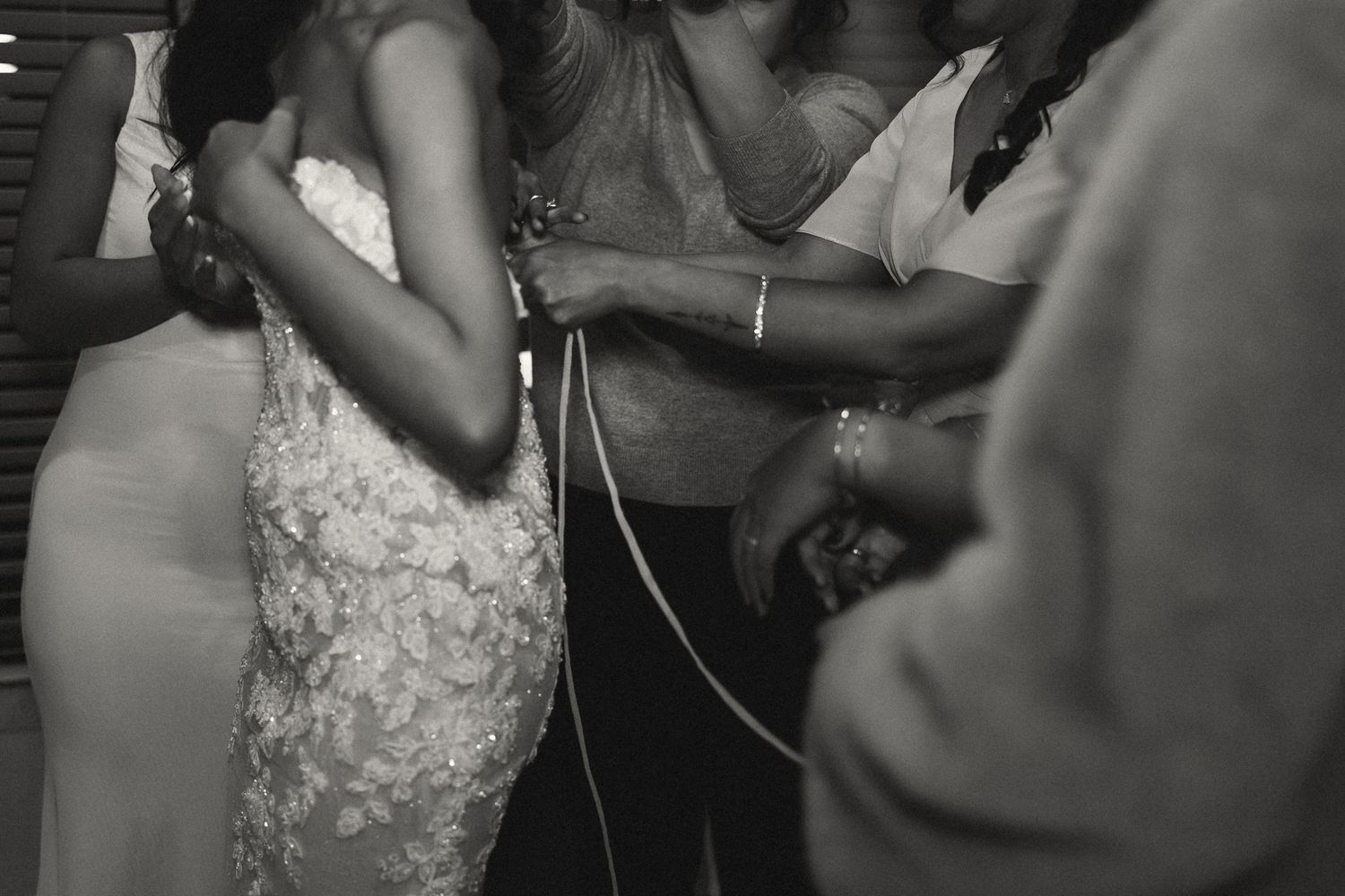 Black and white wedding photo of bride dancing closely with guests at a reception celebration.