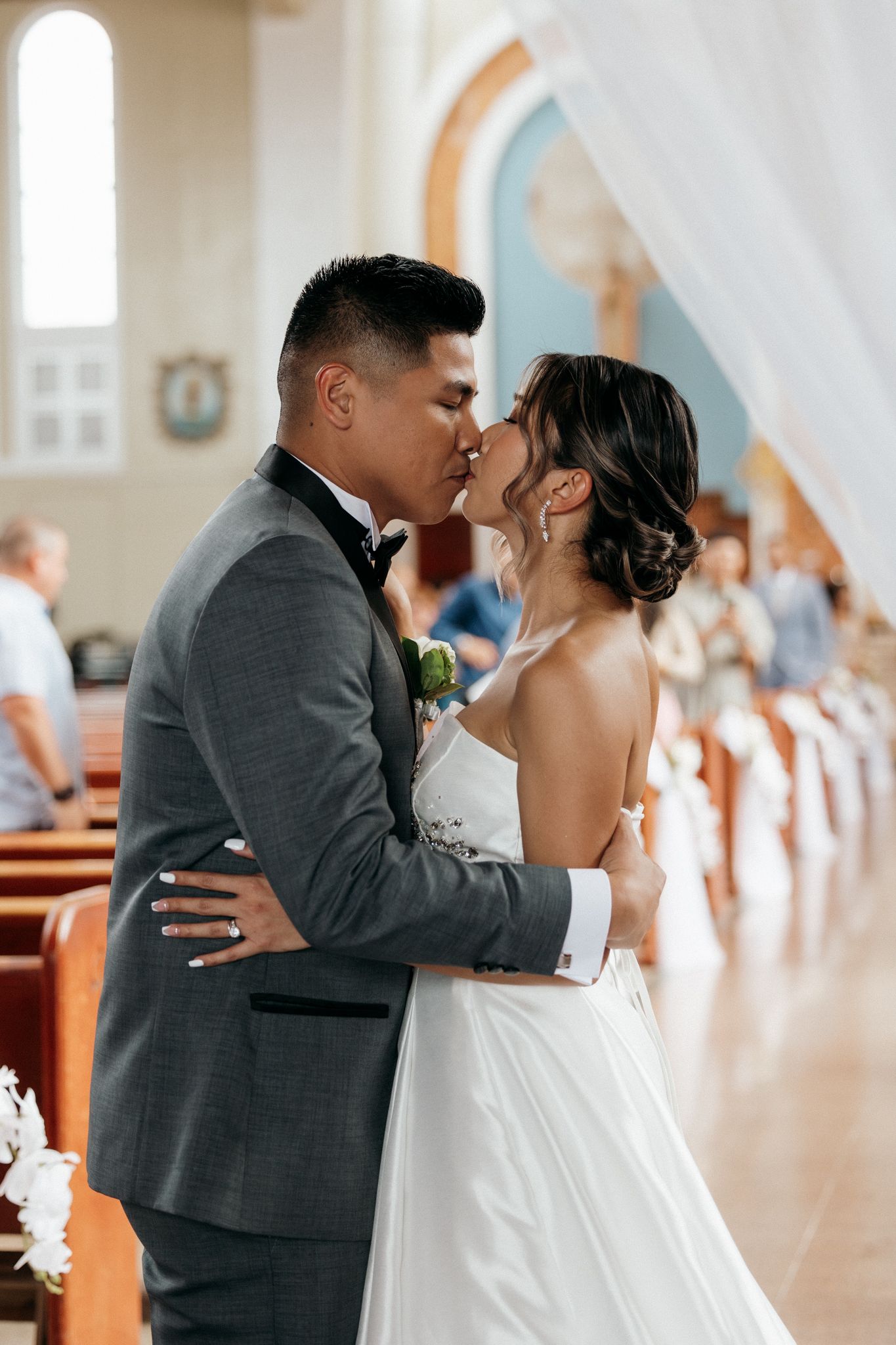 Bride and groom share their first kiss at the altar inside a beautiful church during their wedding ceremony.