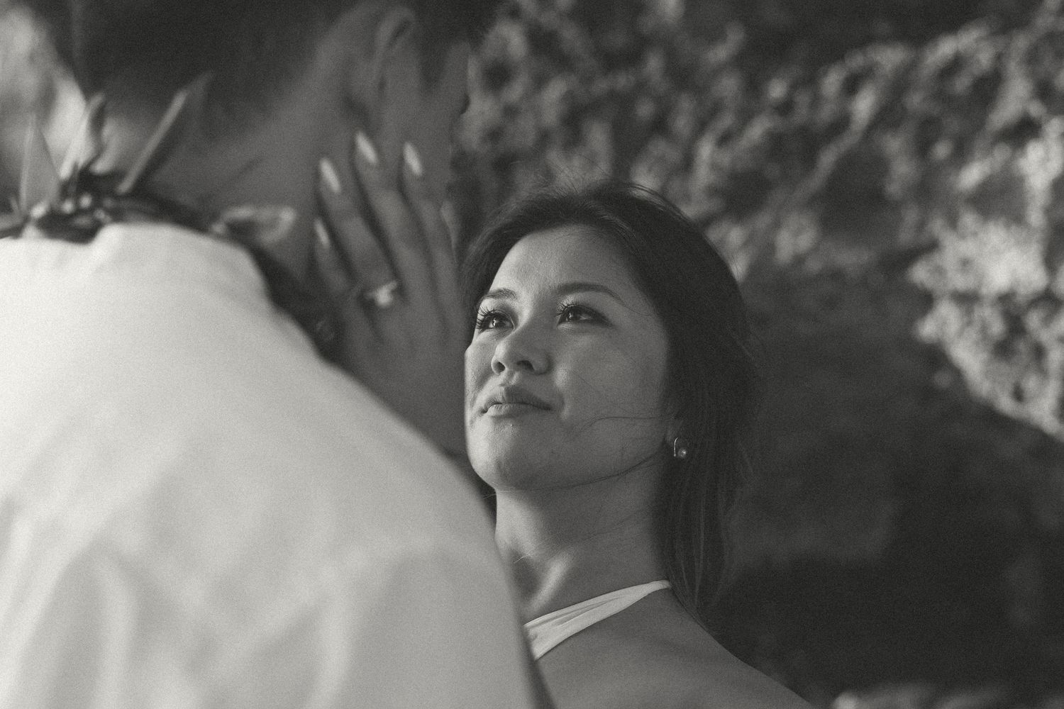 Black and white photo of a woman gazing lovingly at her partner during a romantic outdoor wedding ceremony.