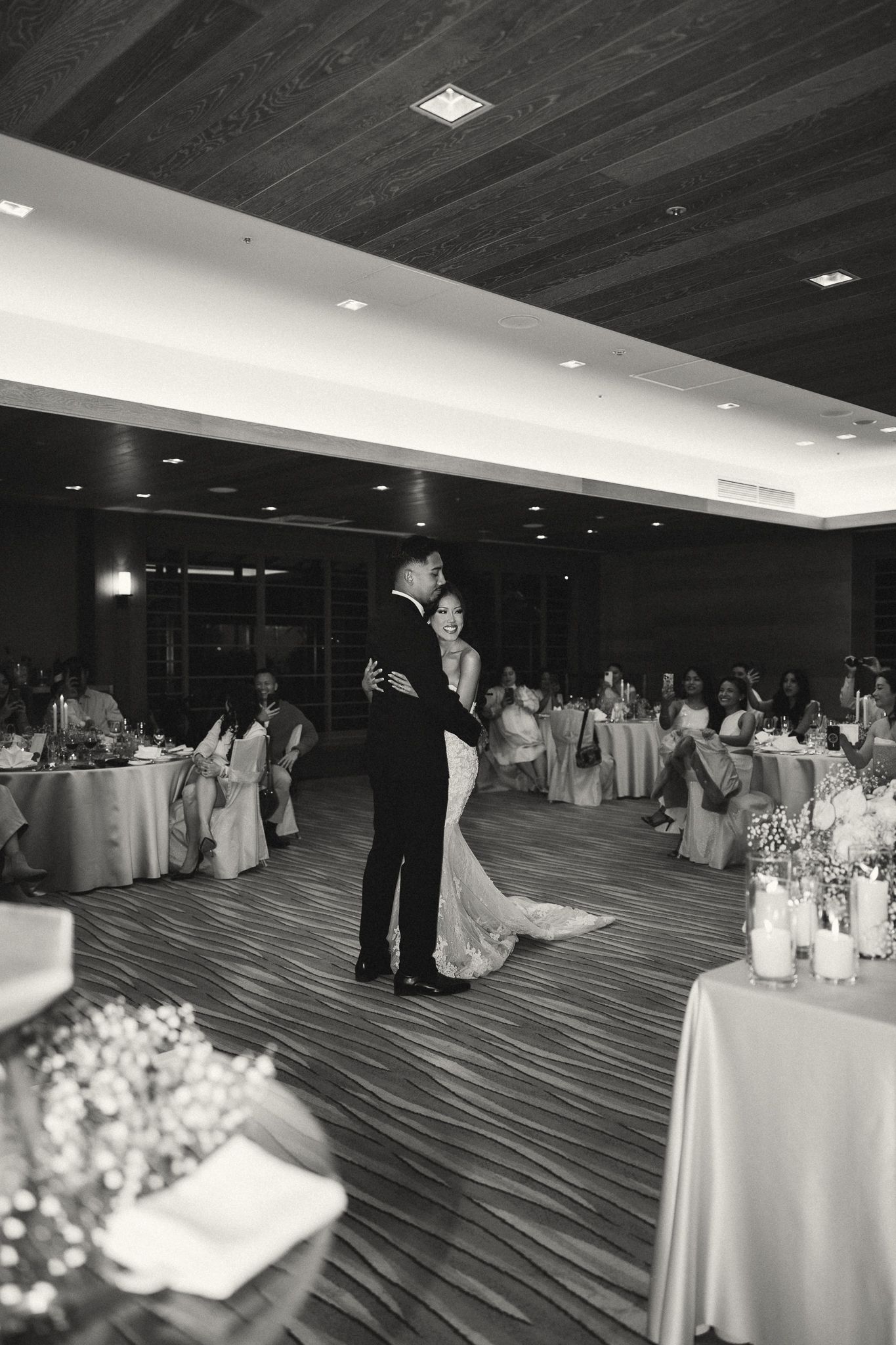 Black and white photo of a bride and groom sharing their first dance at an elegant wedding reception.