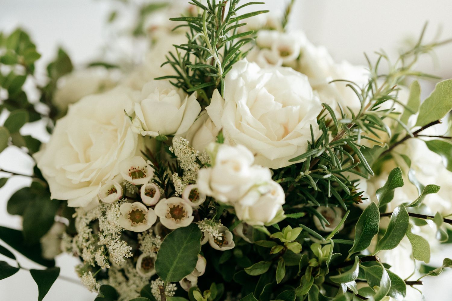 Elegant white rose and greenery bouquet with rosemary accents, perfect for weddings or special occasions.