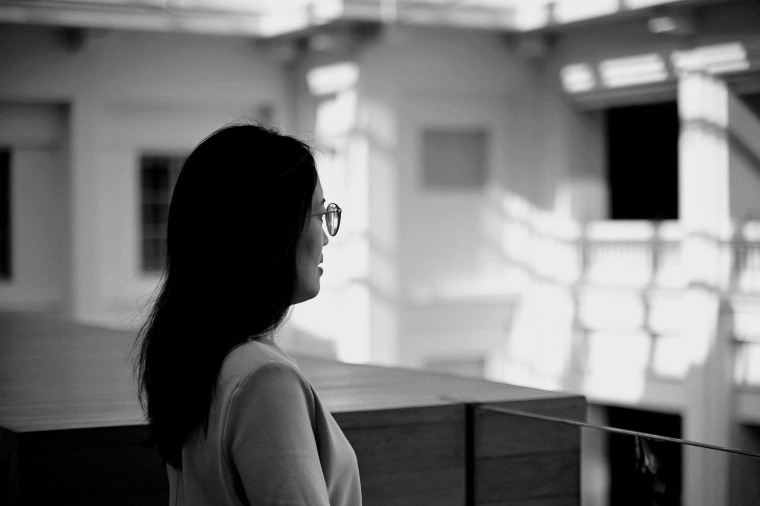 Black and white profile portrait of a young woman with glasses gazing away.
