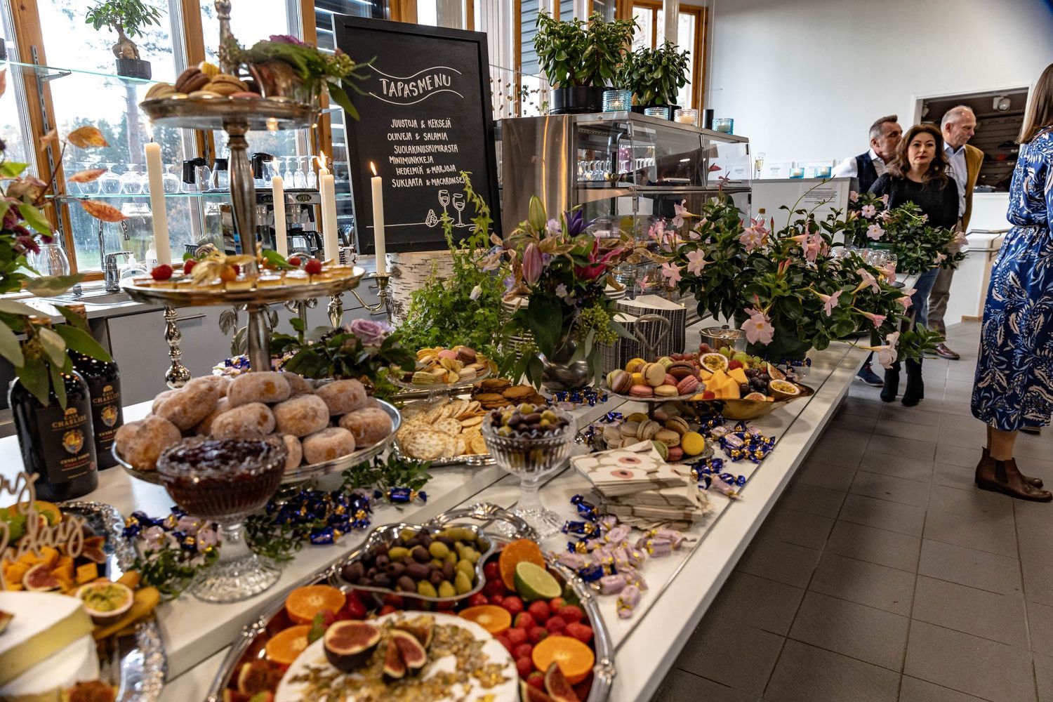 Elegant catering buffet table with fresh fruits, flowers, and gourmet foods at an upscale event venue.