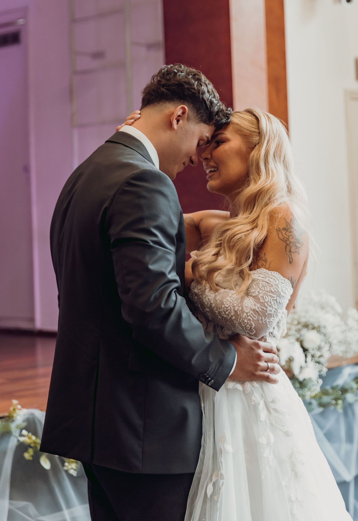 Bride and groom sharing romantic forehead touch moment during first dance at elegant wedding venue.