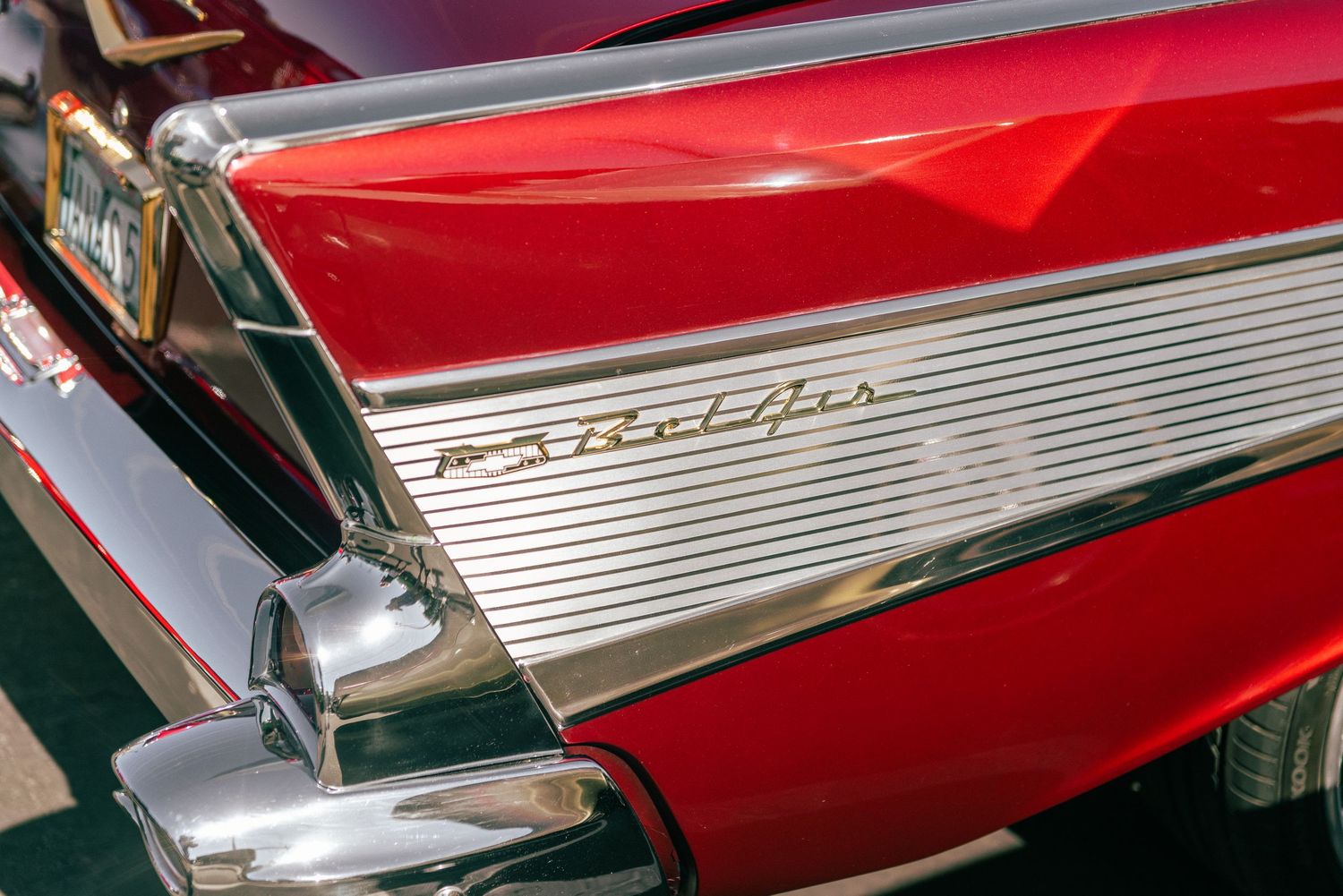 Iconic tail fin and Bel Air script emblem on a restored red 1957 Chevrolet classic car.