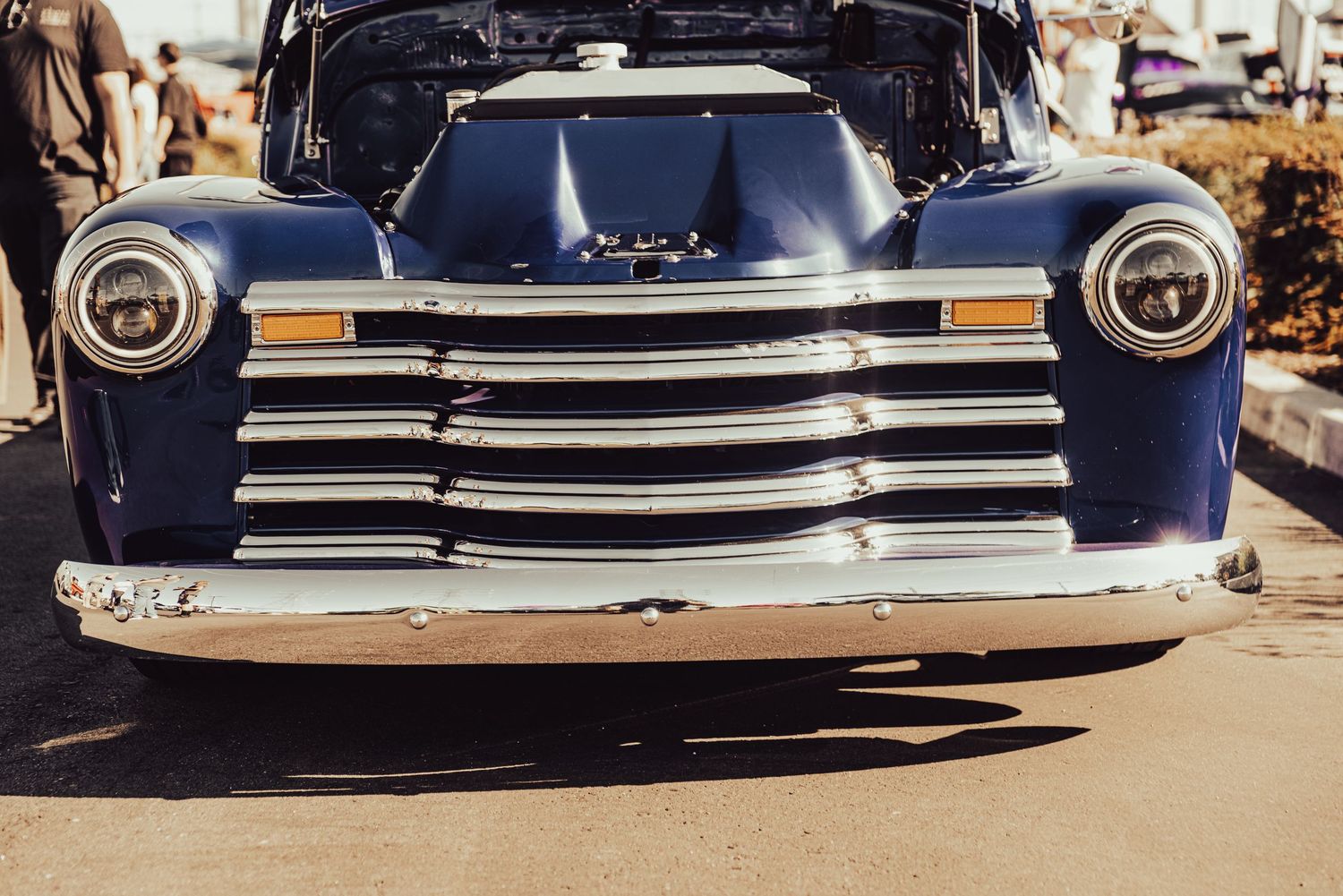 Vintage blue Chevrolet pickup truck front view featuring chrome grille and dual headlights in sunlight.