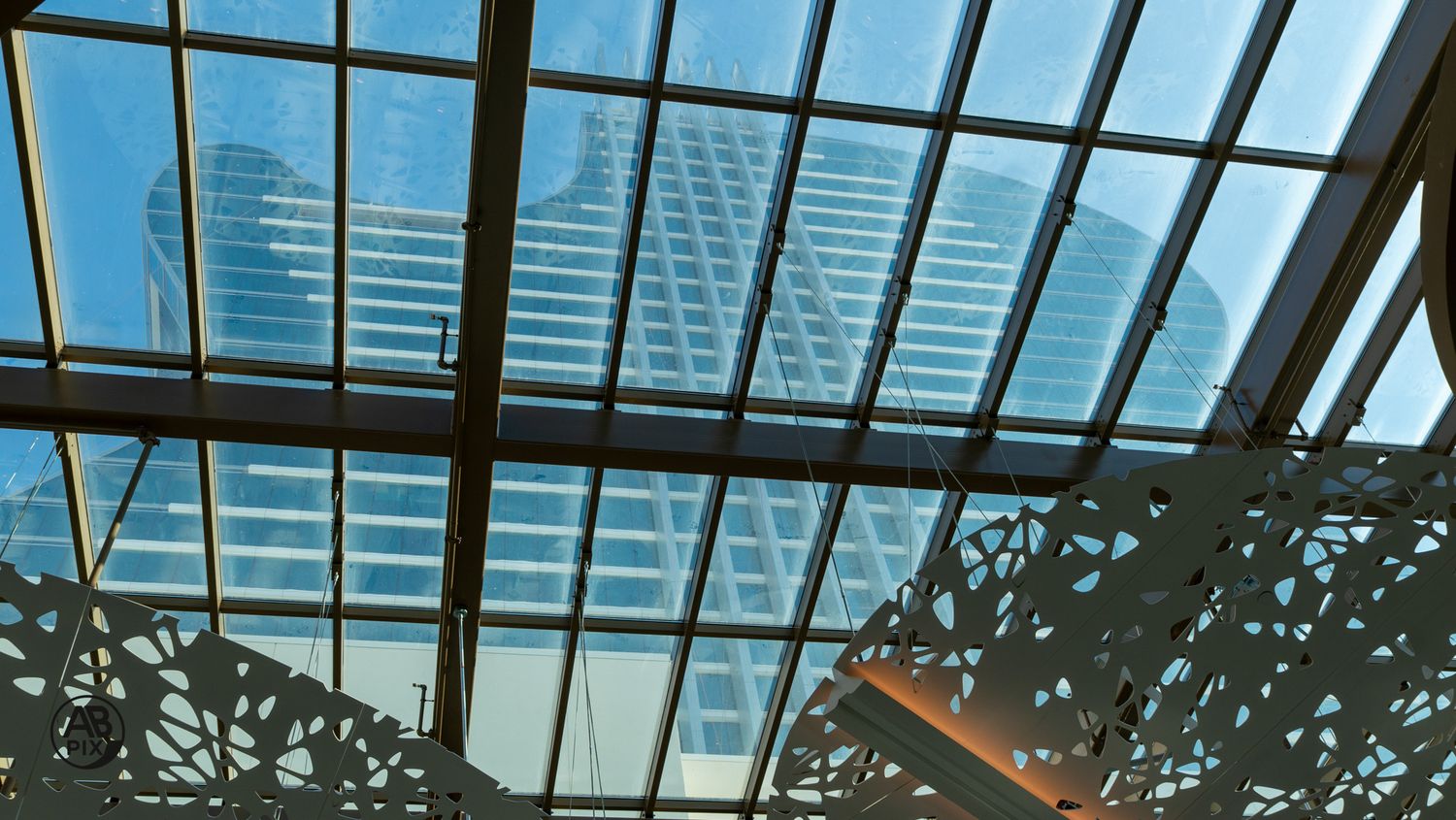 Glass ceiling skylight revealing modern blue skyscrapers in luxury shopping center.