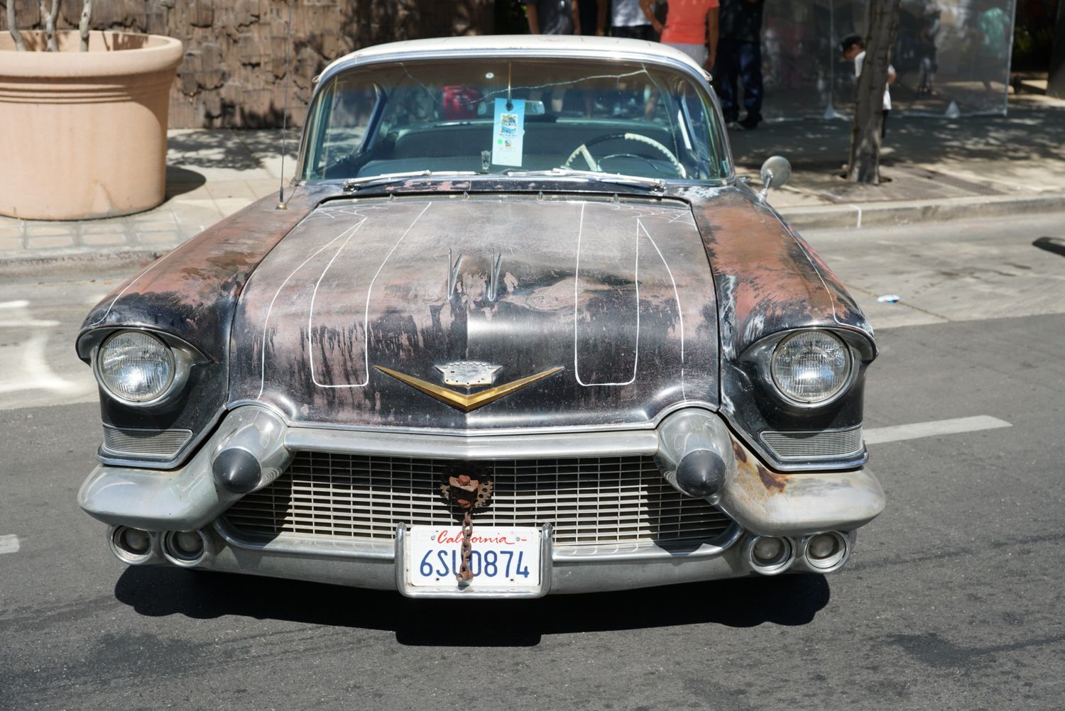 A vintage 1957 Cadillac with custom painted hood art and weathered patina finish at a car show.