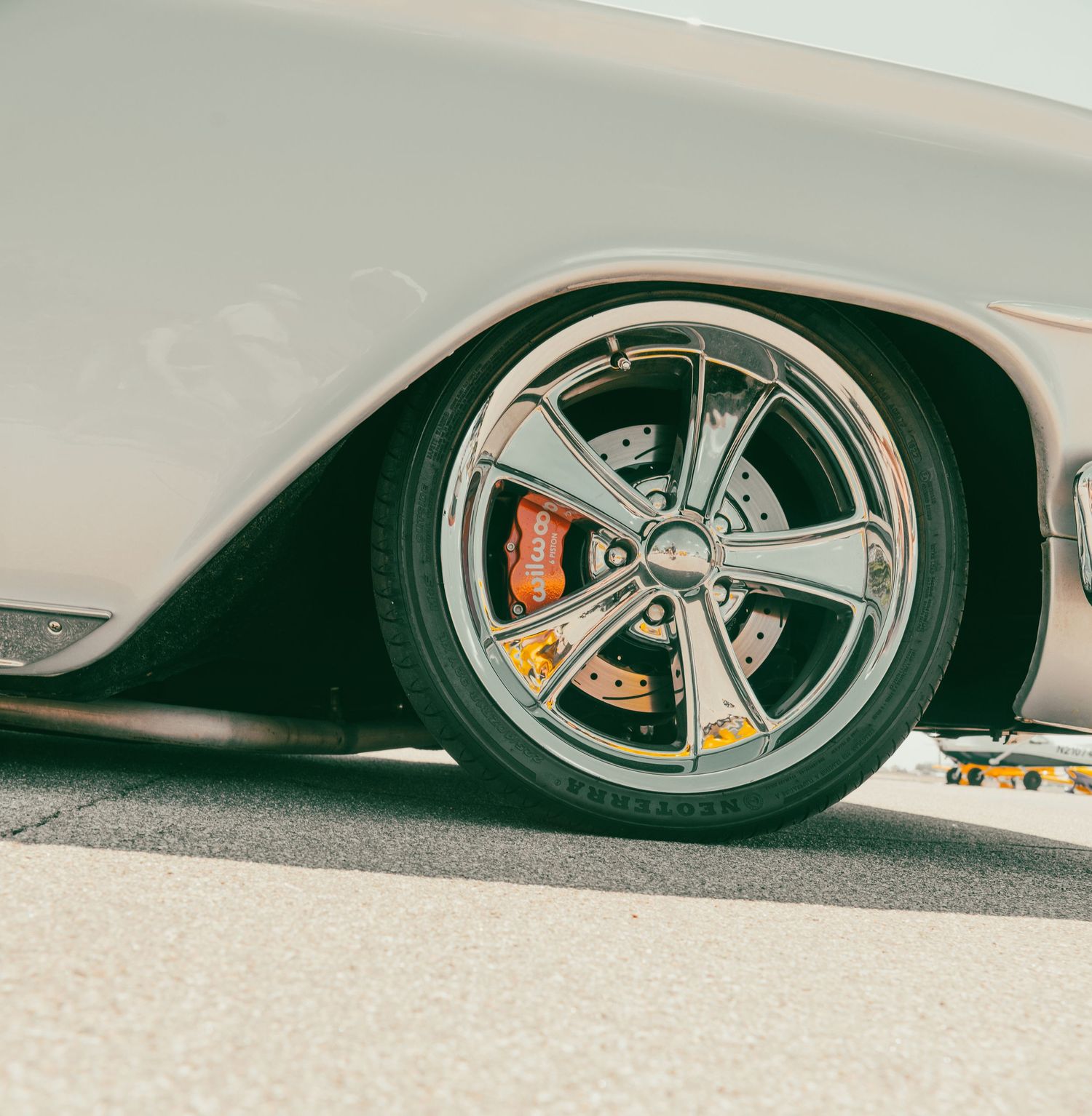 Close-up of chrome spinner wheels on a classic lowrider car with red brake calipers.