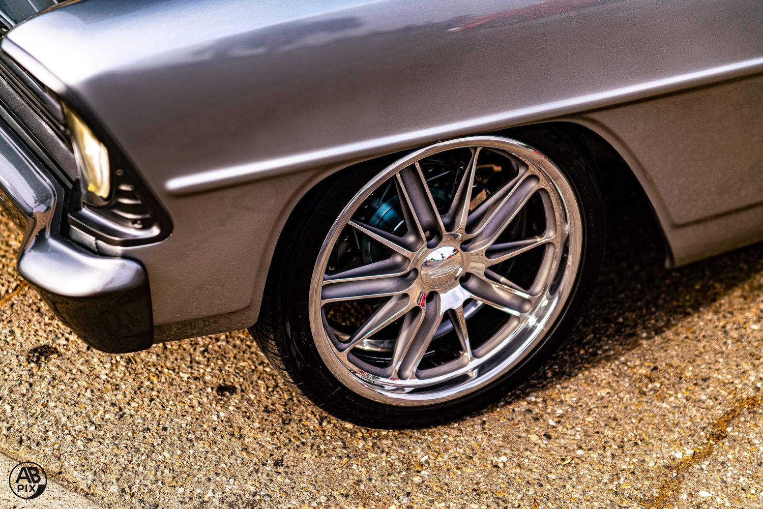 Silver classic Chevrolet with chrome multi-spoke custom wheel, low angle detail shot.