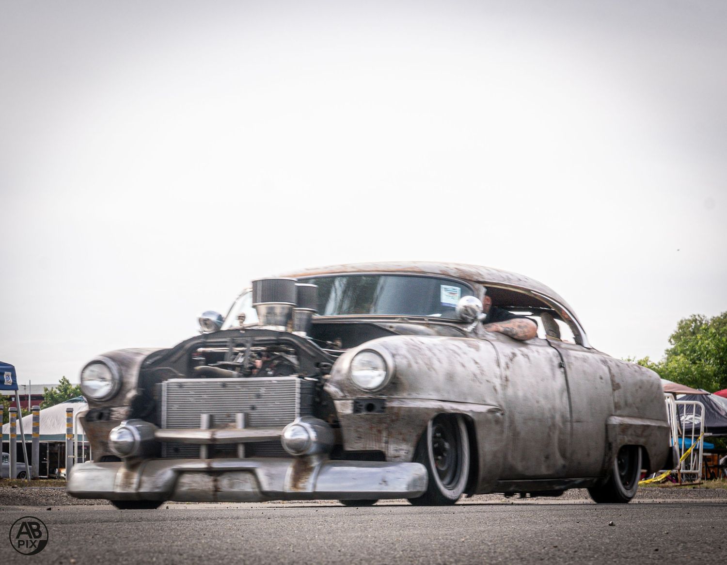 Rustic rat rod classic car with exposed engine and slammed stance at car show.
