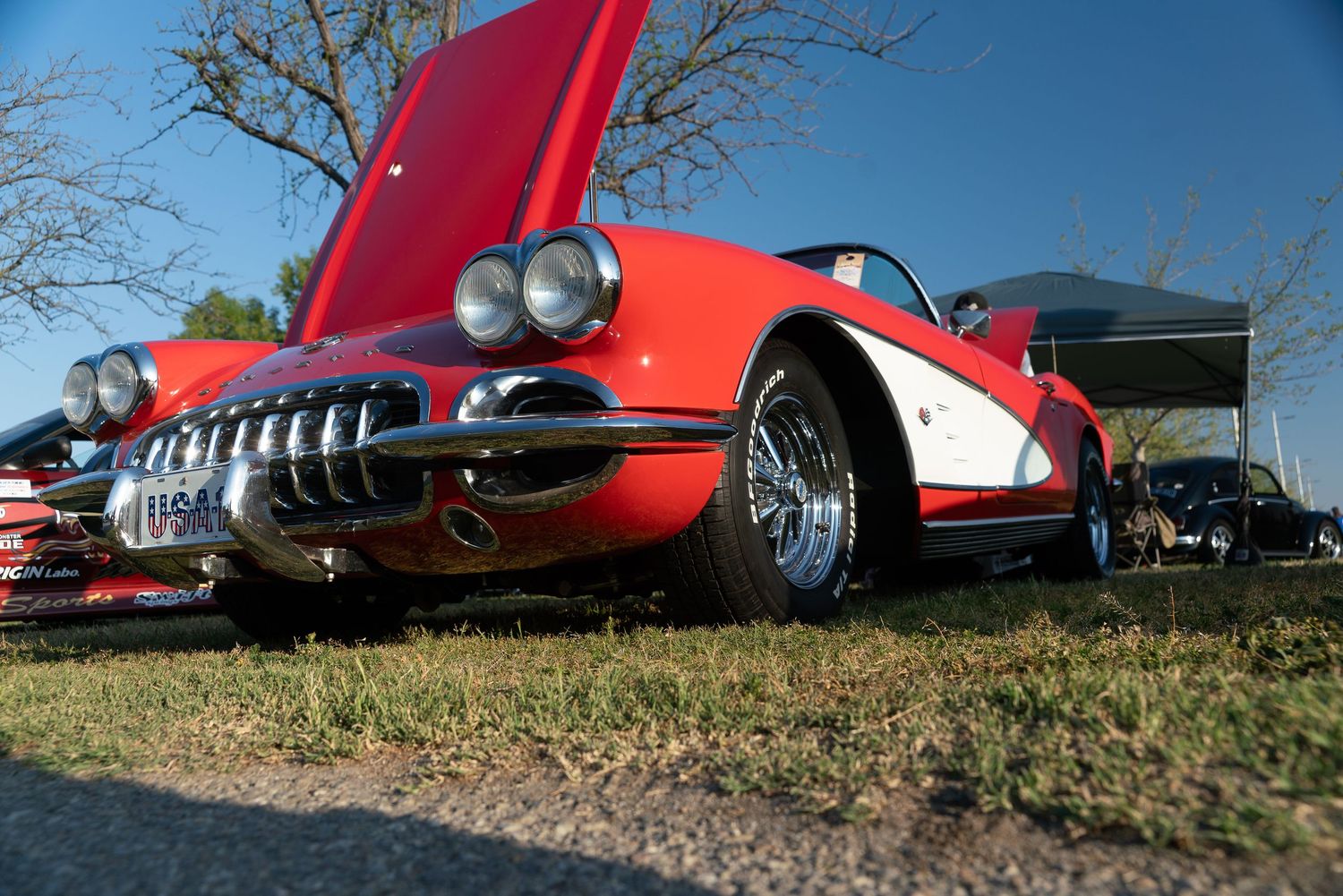 Red 1959 Corvette classic car on display at outdoor car show, low angle view showcasing chrome grille.