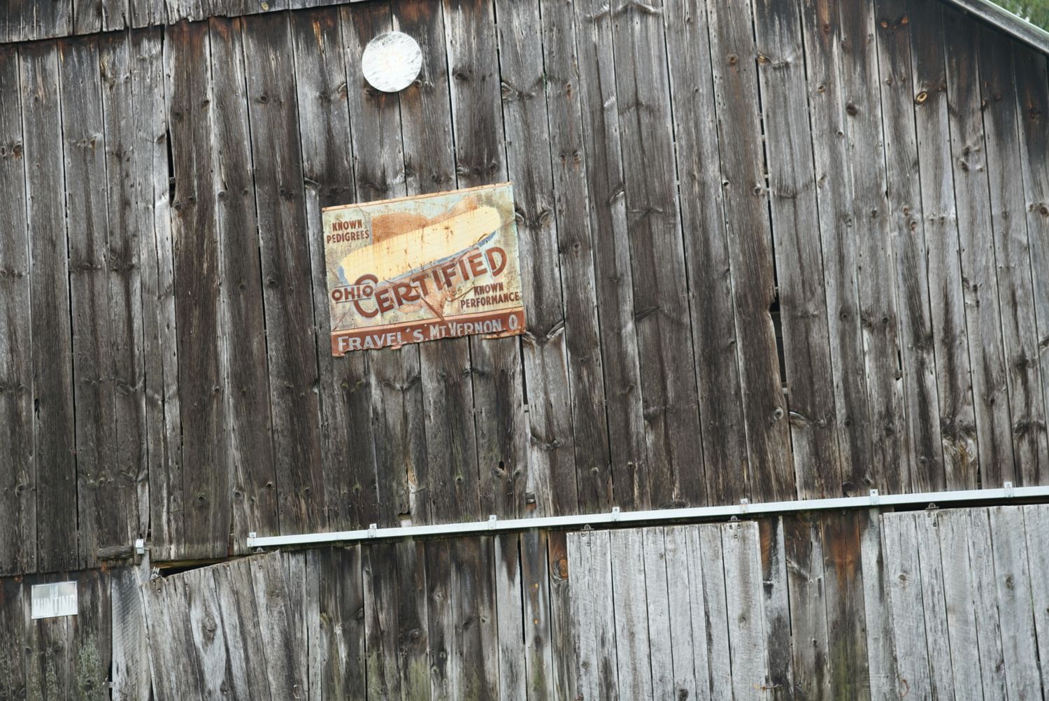 Weathered wooden barn wall displaying a vintage certified seed company advertisement sign.