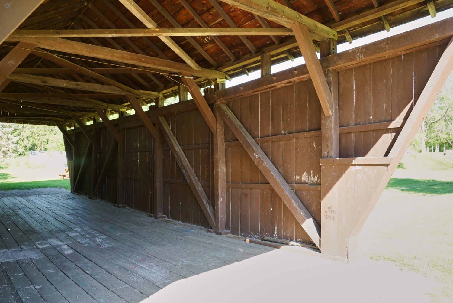 Interior view of historic wooden covered bridge showing timber frame construction and diagonal bracing.