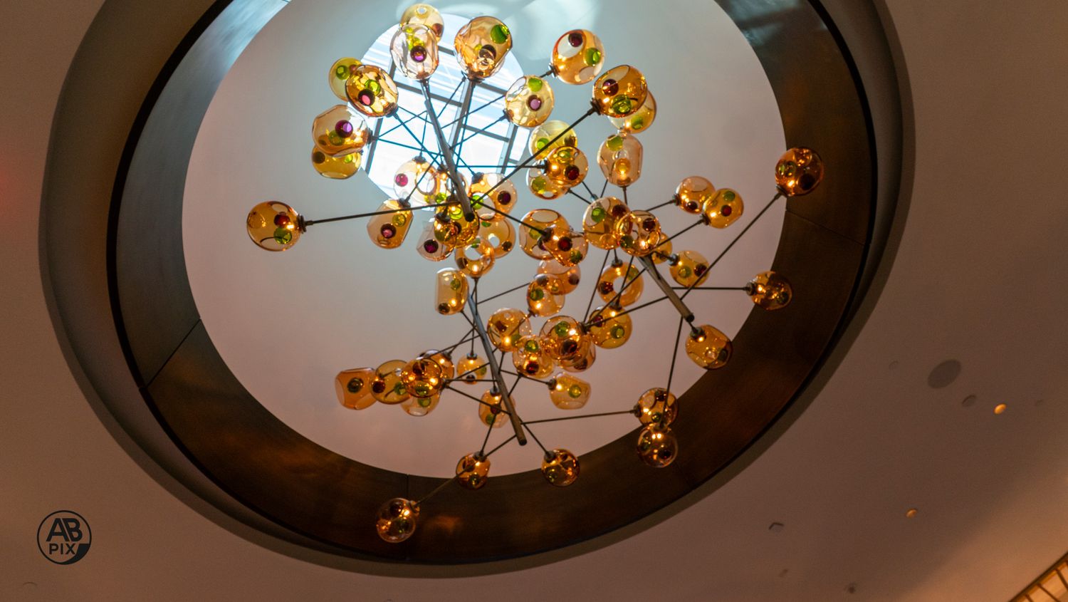 Golden amber glass ball chandelier with branching metal arms hanging from circular ceiling medallion.