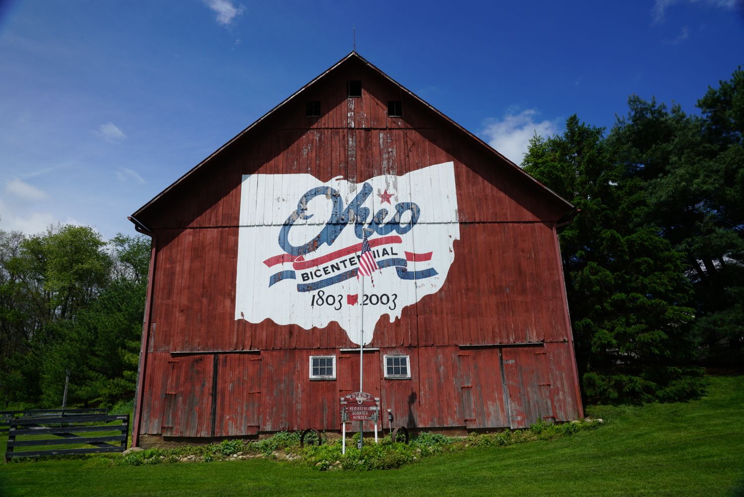 Red Ohio bicentennial barn with state outline painted on side, celebrating 1803-2003 anniversary.
