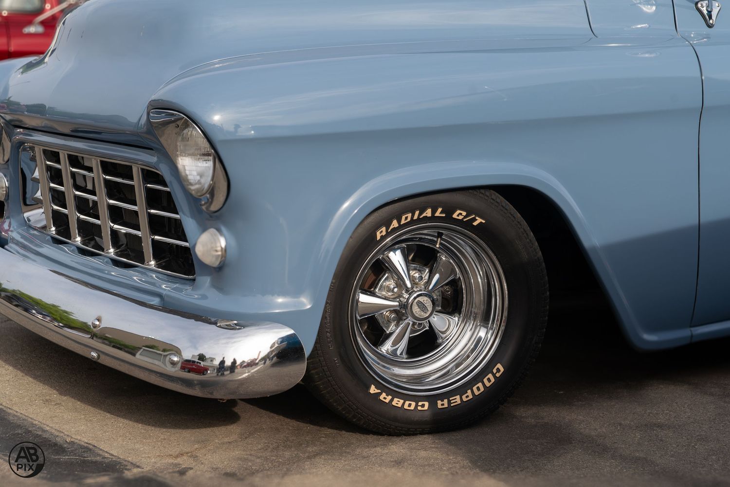 Close-up of a classic blue Chevrolet truck featuring a chrome grille and Cooper Cobra Radial GT white letter tire.
