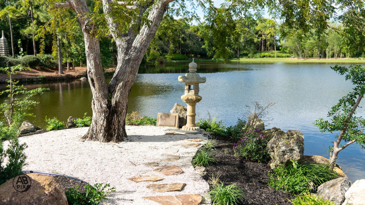 Stone lantern beside a calm lake along a Japanese garden stone path.